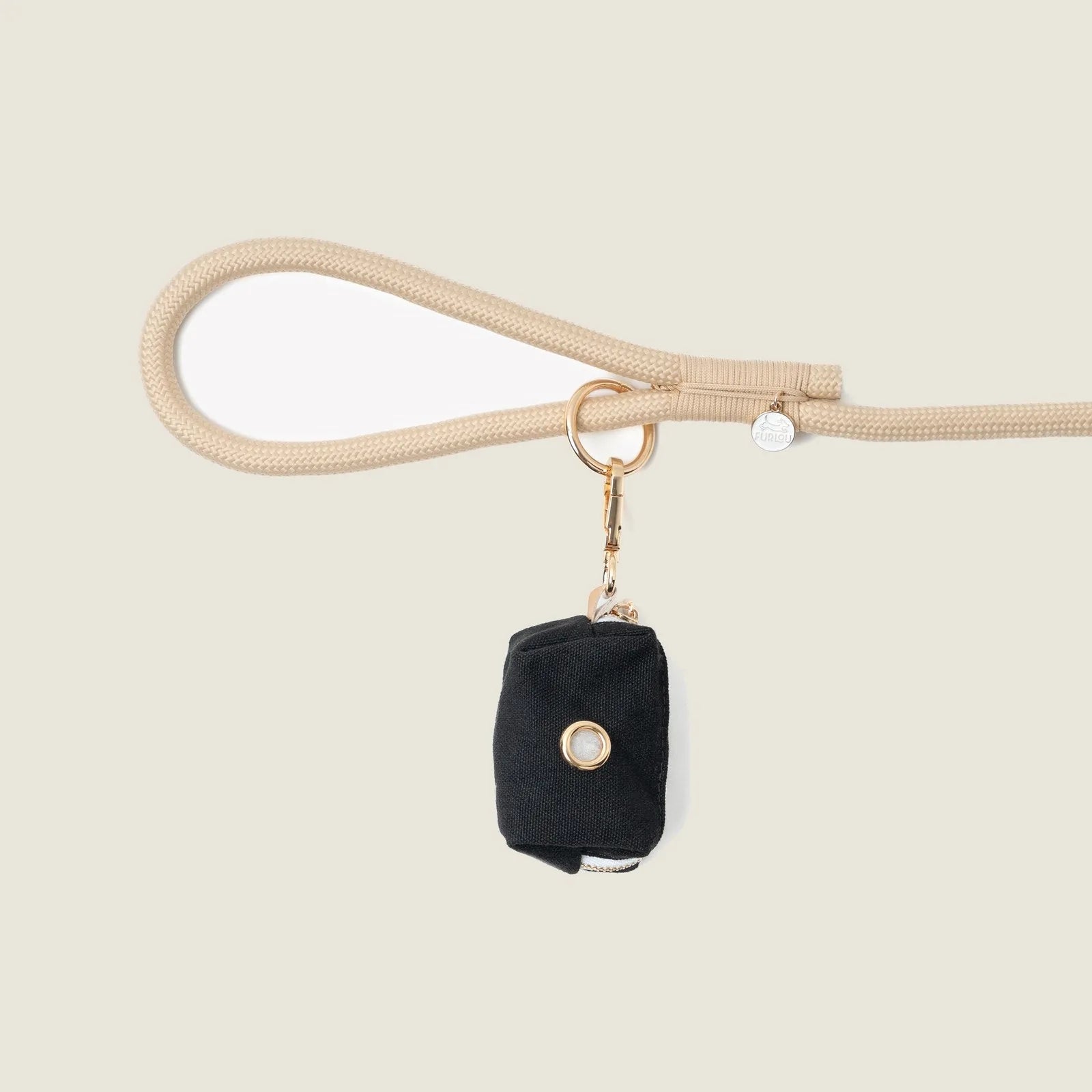 Black poop bag holder by FURLOU, attached to a beige leash, featuring a gold clip and button detail.