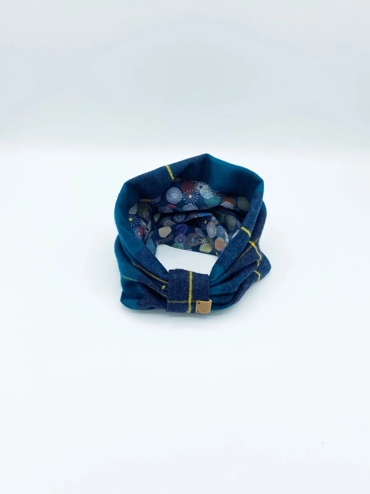Reversible pet snood featuring a teal exterior with yellow plaid and a colorful floral interior, crafted from soft cotton...