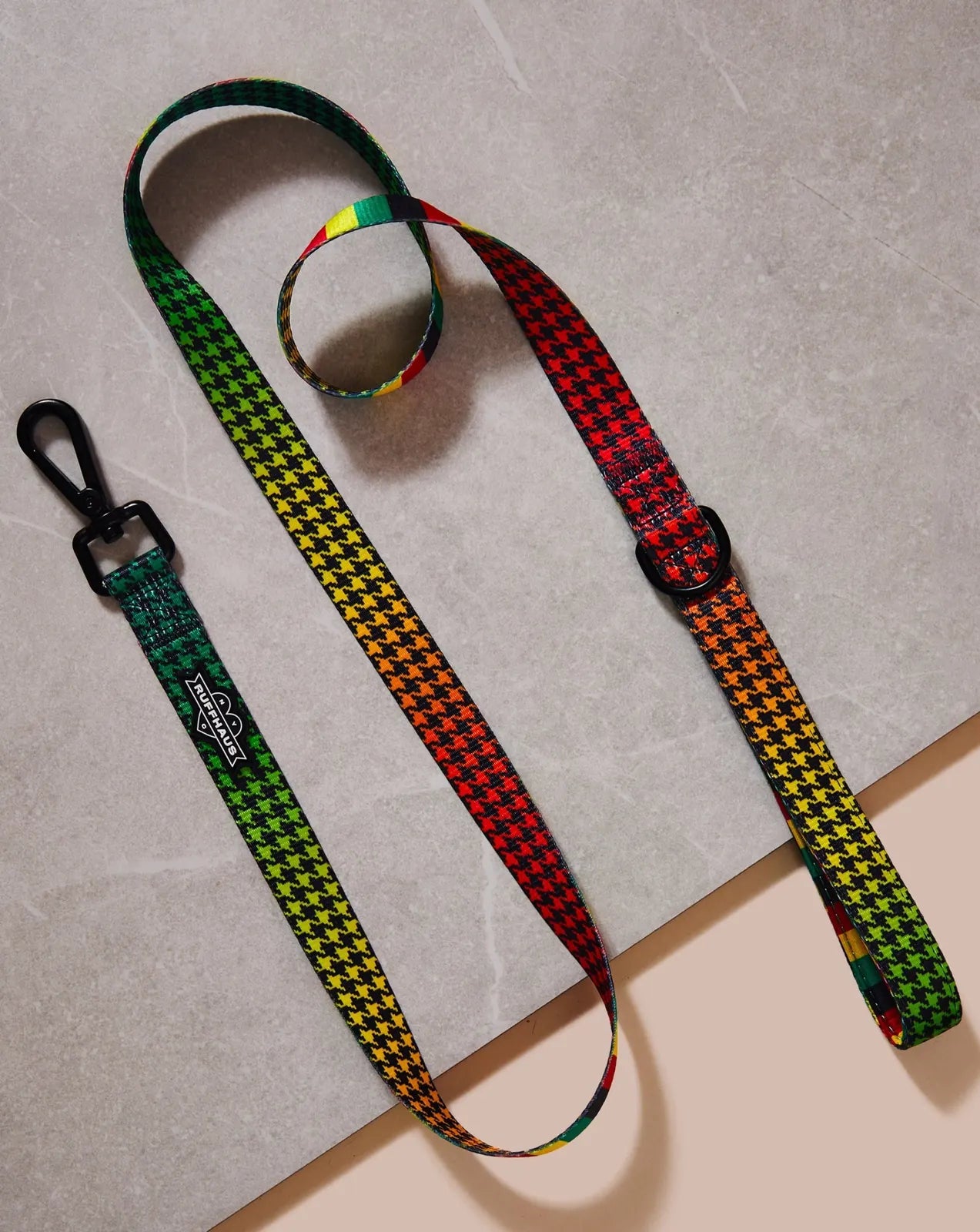 Colorful Rasta-patterned dog leash featuring a cushioned neoprene handle and swivel snap clasp, laid on a neutral surface.