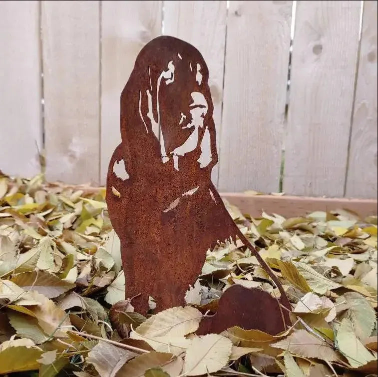 Rust-colored Bloodhound metal silhouette in leaves, showcasing intricate cutouts and a dog shape in a natural outdoor sett...