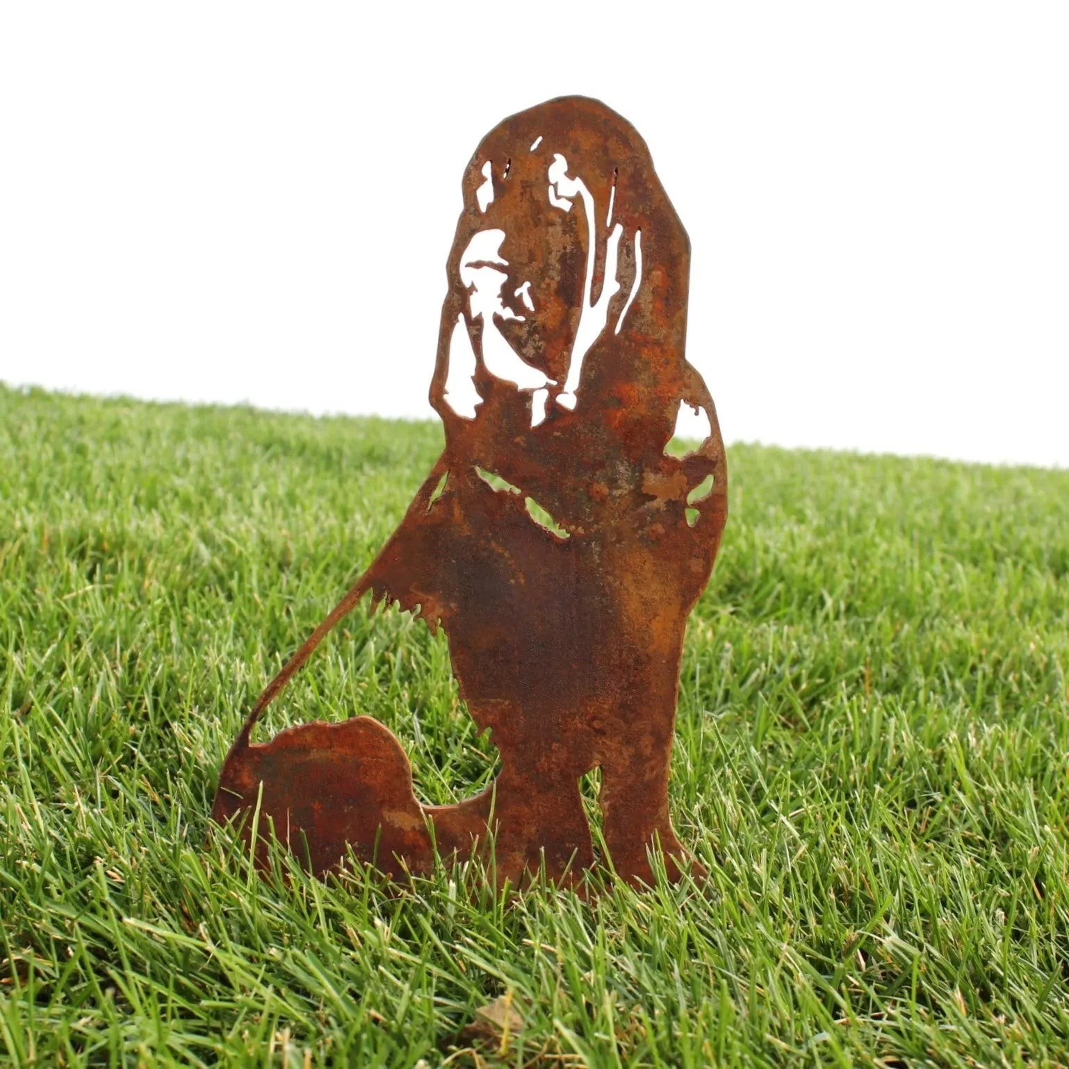 Rusty metal silhouette of a Bloodhound on green grass, showcasing intricate detail and outdoor decor charm.