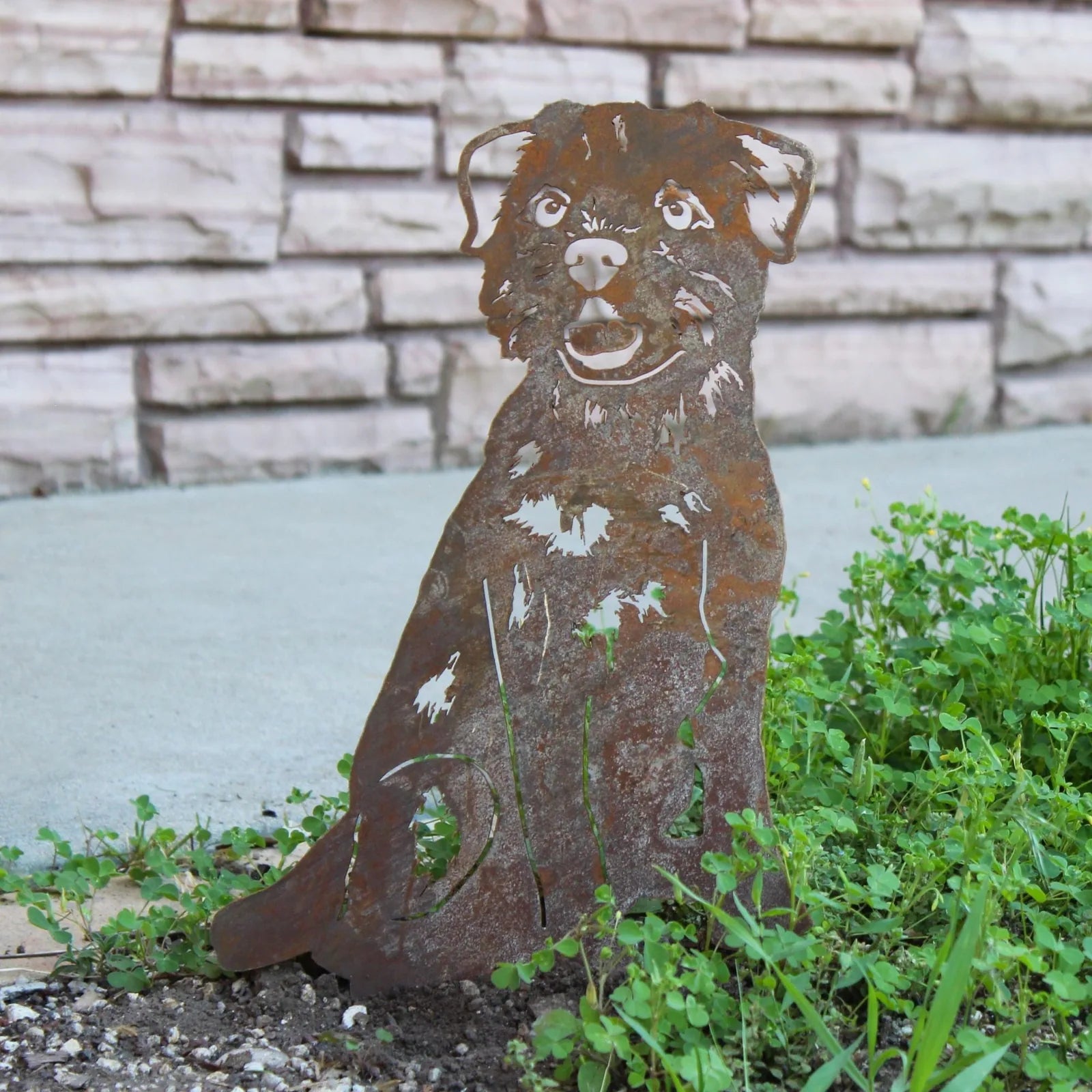 Border Terrier silhouette in weathered Corten steel, set against green grass and stone backdrop, adds rustic charm to outd...