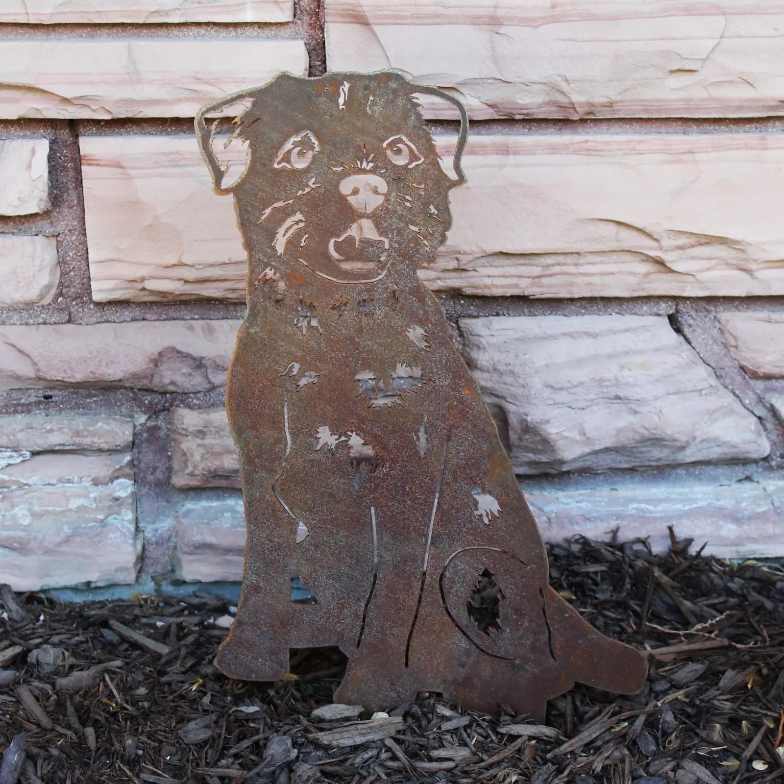 Rusty Corten steel Border Terrier silhouette standing against a stone wall, perfect for garden or outdoor decor.