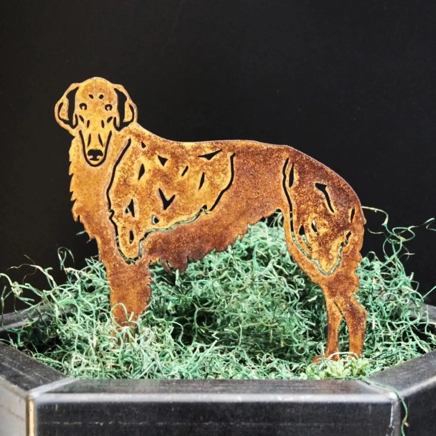Borzoi dog silhouette in rusted Corten steel, featuring detailed cut-outs, set in green moss on a black background.