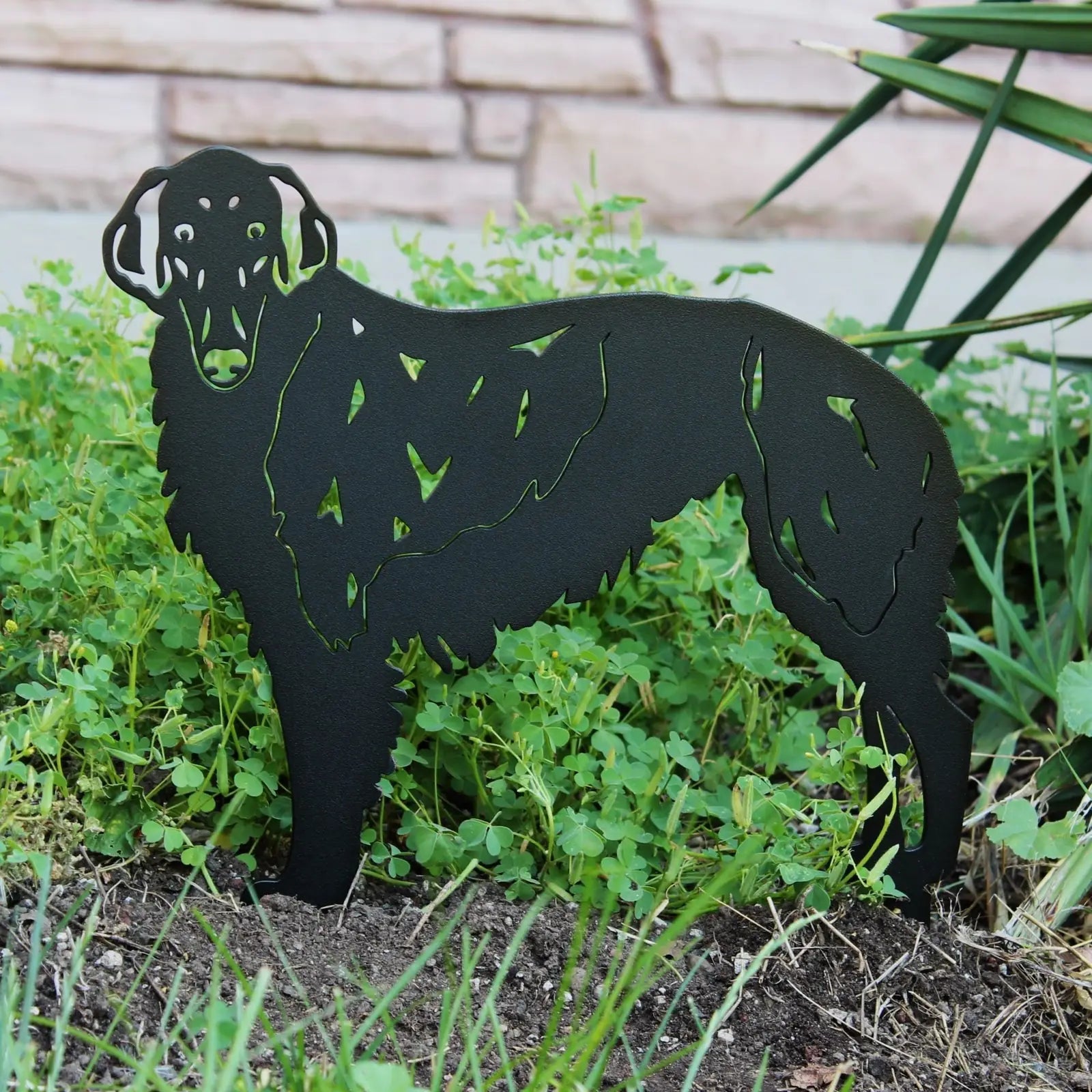 Borzoi metal art silhouette in matte black, blending seamlessly into a garden setting with lush greenery.