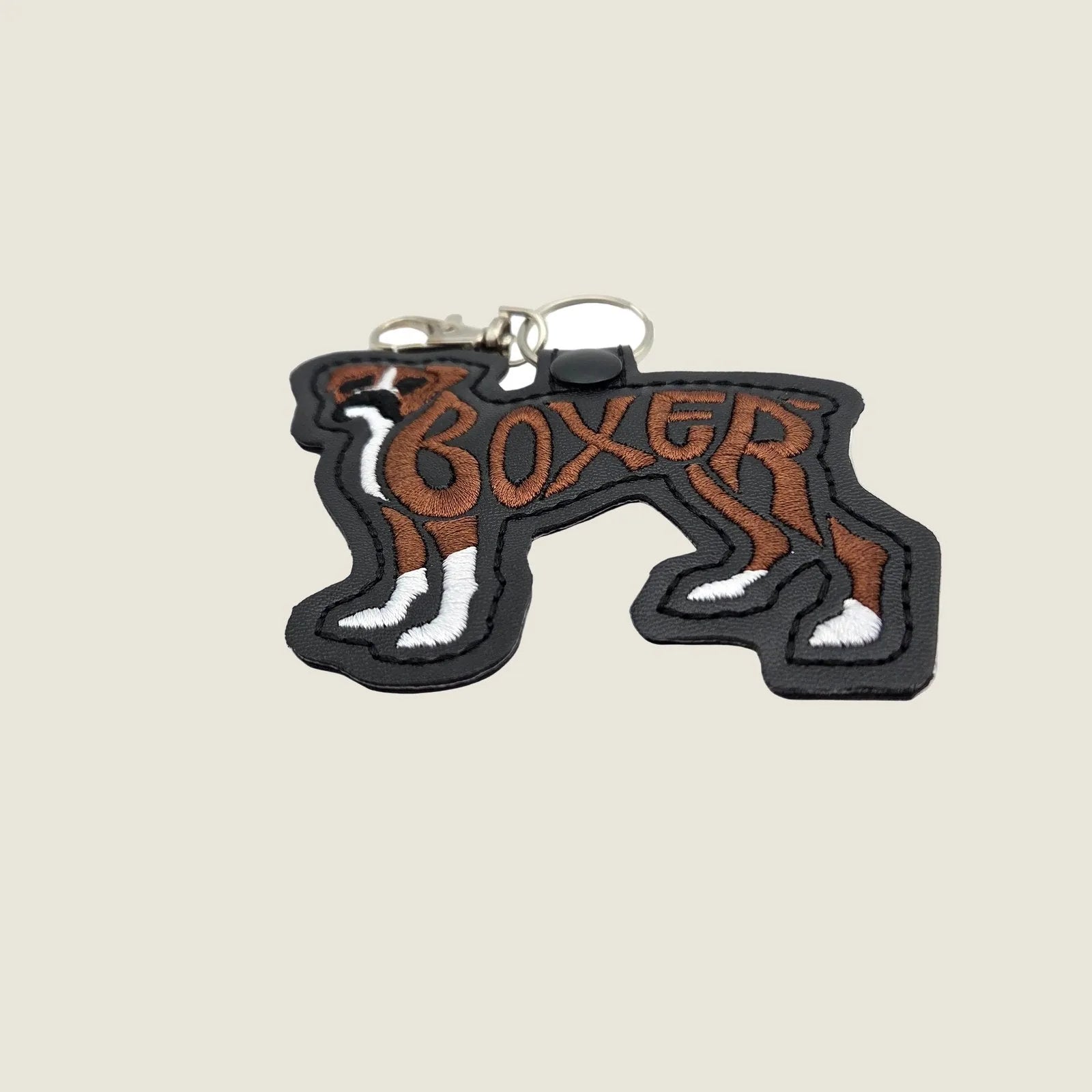 Embroidered brown and white Boxer dog keychain tab with black faux leather, featuring detailed stitching and a metal clasp.