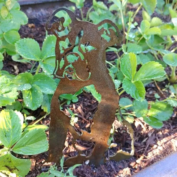 Rusty Corten steel Boxer silhouette decor standing among lush green strawberry plants, adding a charming outdoor touch.