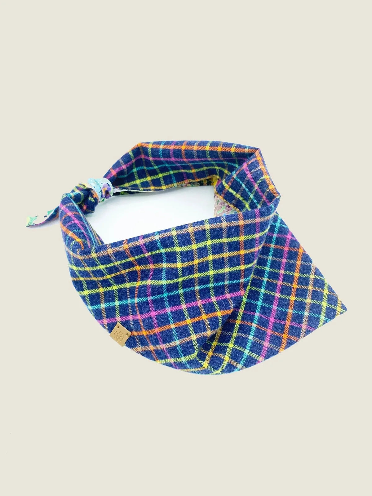 Reversible dog bandana in navy flannel with a colorful plaid pattern, featuring a secure knot tie for easy wear.
