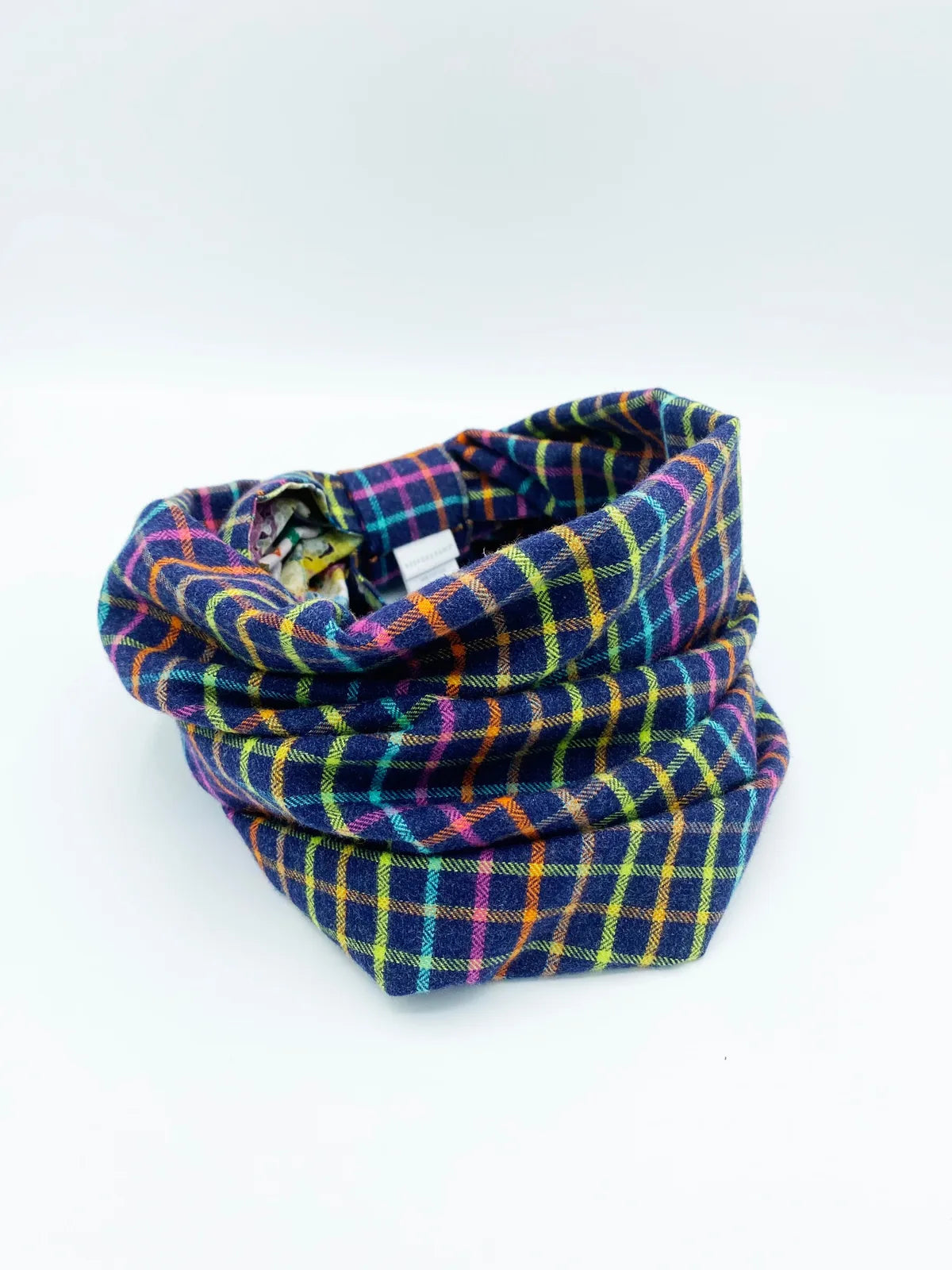 Reversible pet snood featuring black and white plaid with colorful accents, made from soft brushed cotton flannel.