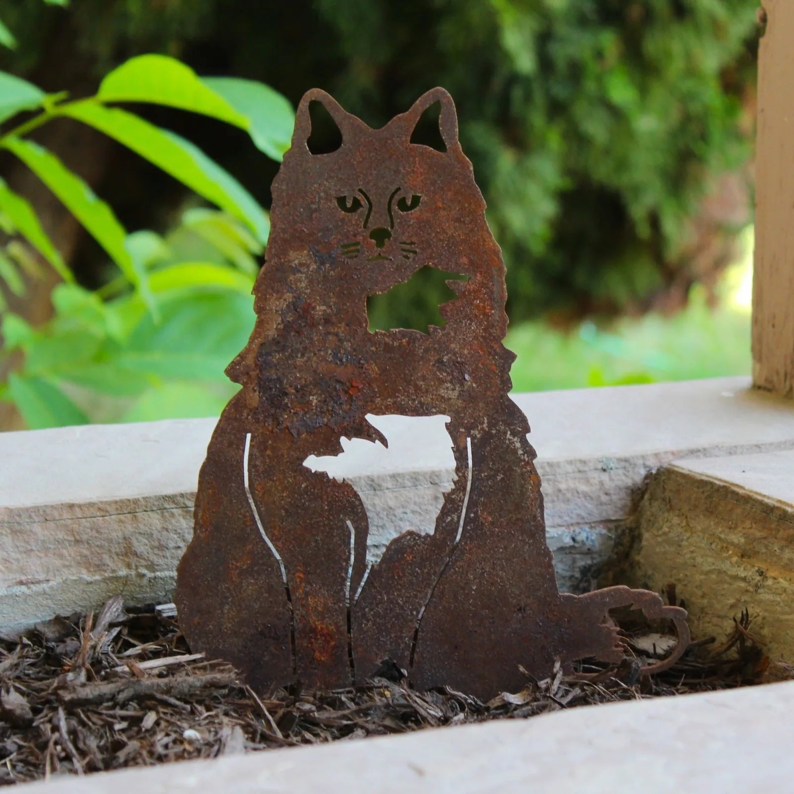 Handmade rusty metal silhouette of a British Longhair cat, perfect for outdoor decor and garden installations.