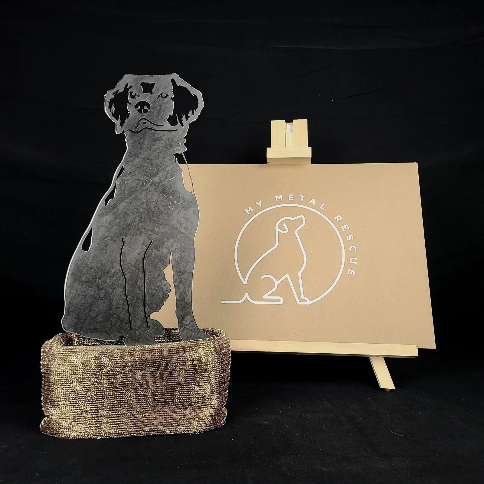 Handmade metal silhouette of a Brittany Spaniel in Corten steel, displayed with a branded backdrop.