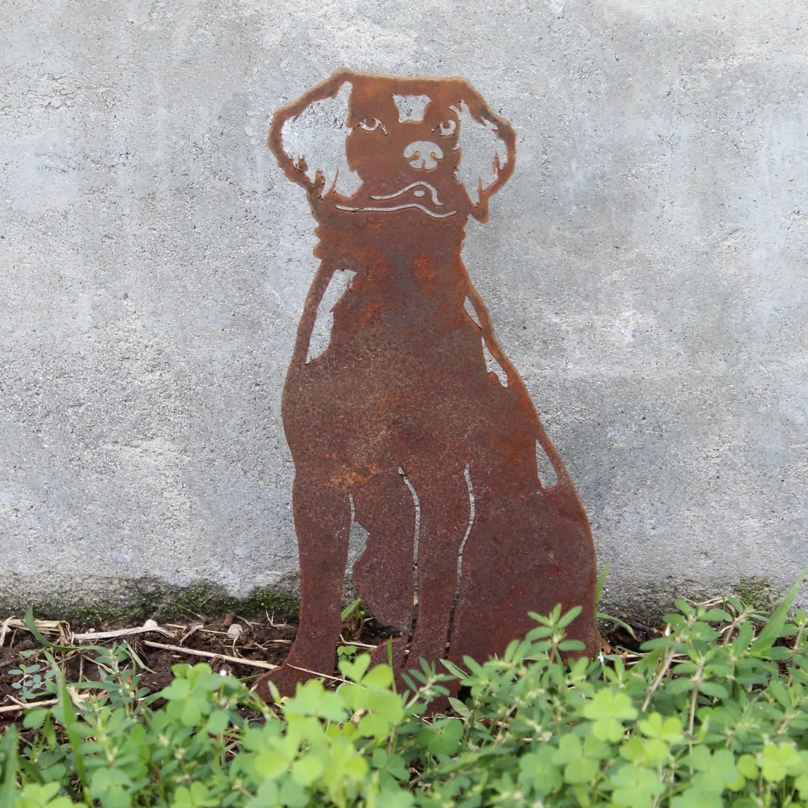 Rusty metal silhouette of a Brittany Spaniel dog, showcased amid greenery, perfect for outdoor decor.