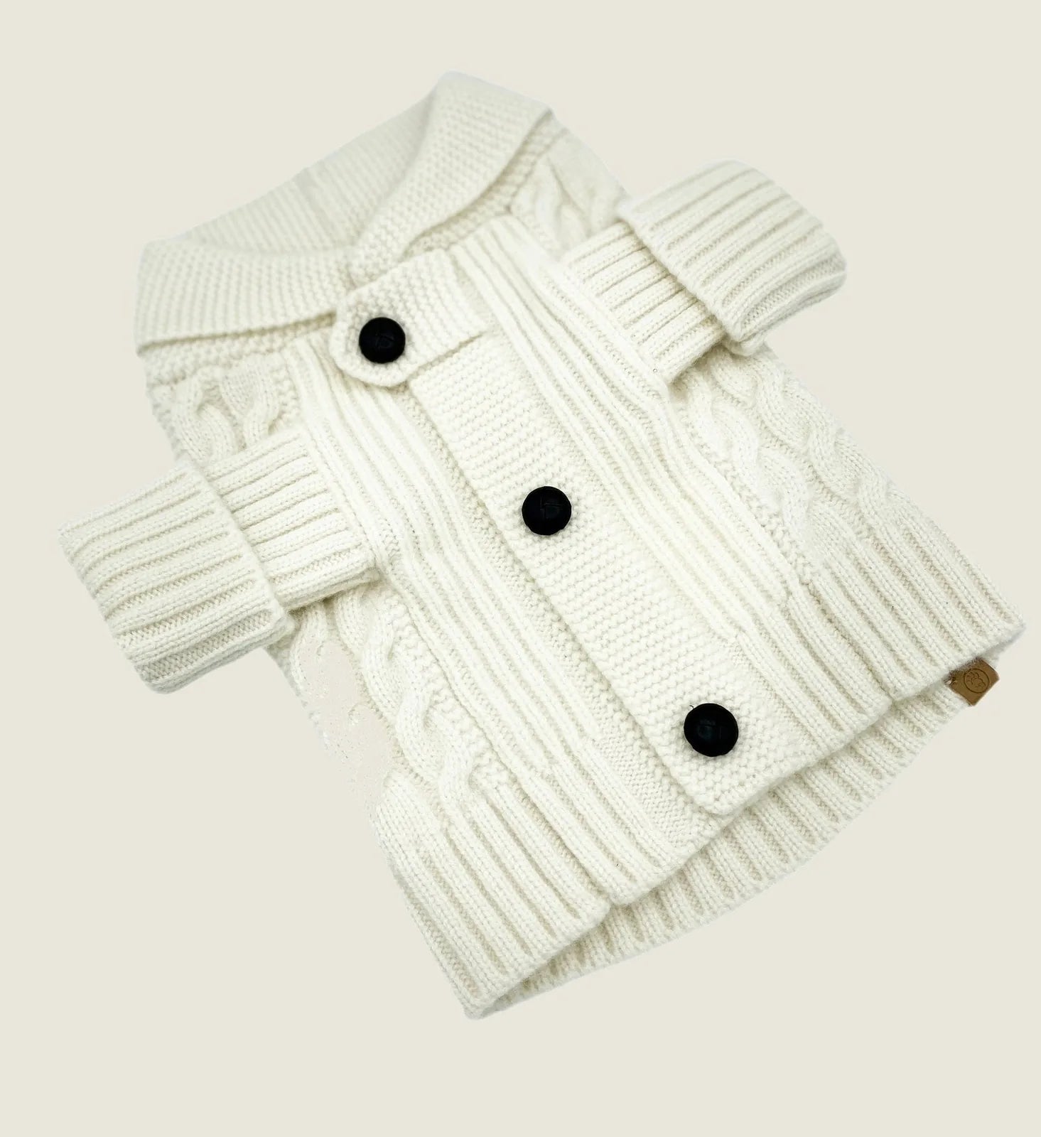 Ivory cashmere dog cardigan with cable knit design, featuring black buttons and ribbed cuffs for added comfort.