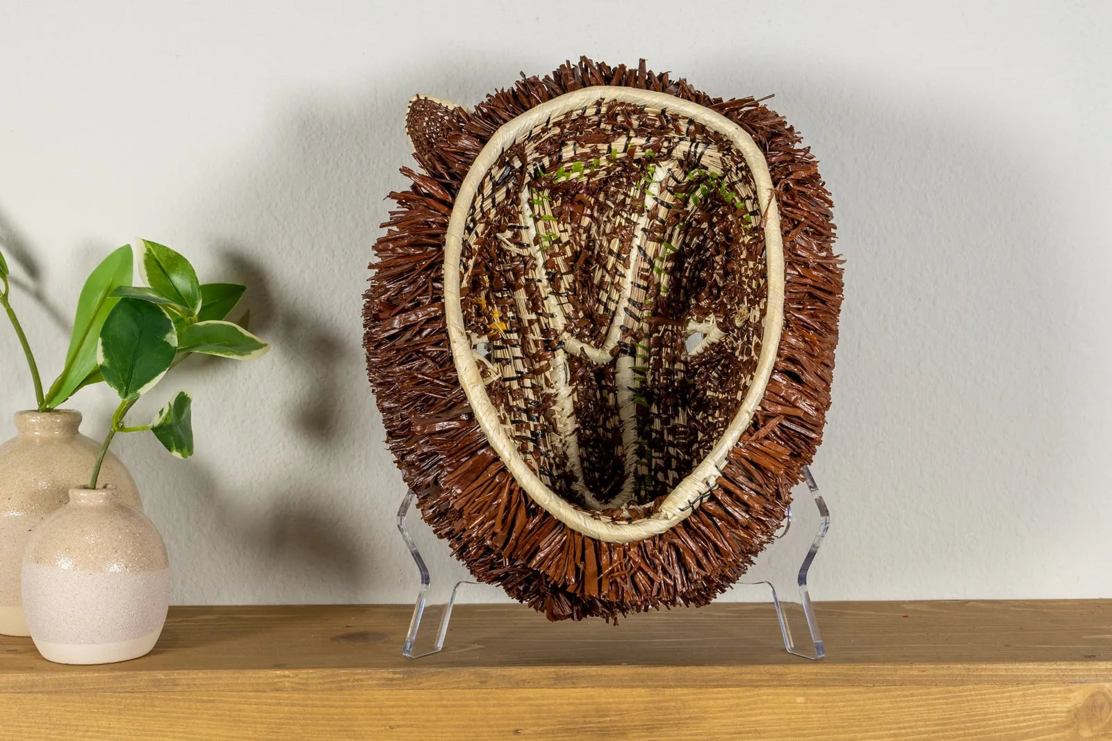 Handwoven brown and white Labradoodle dog mask made from reeds, featuring traditional patterns and natural colors.