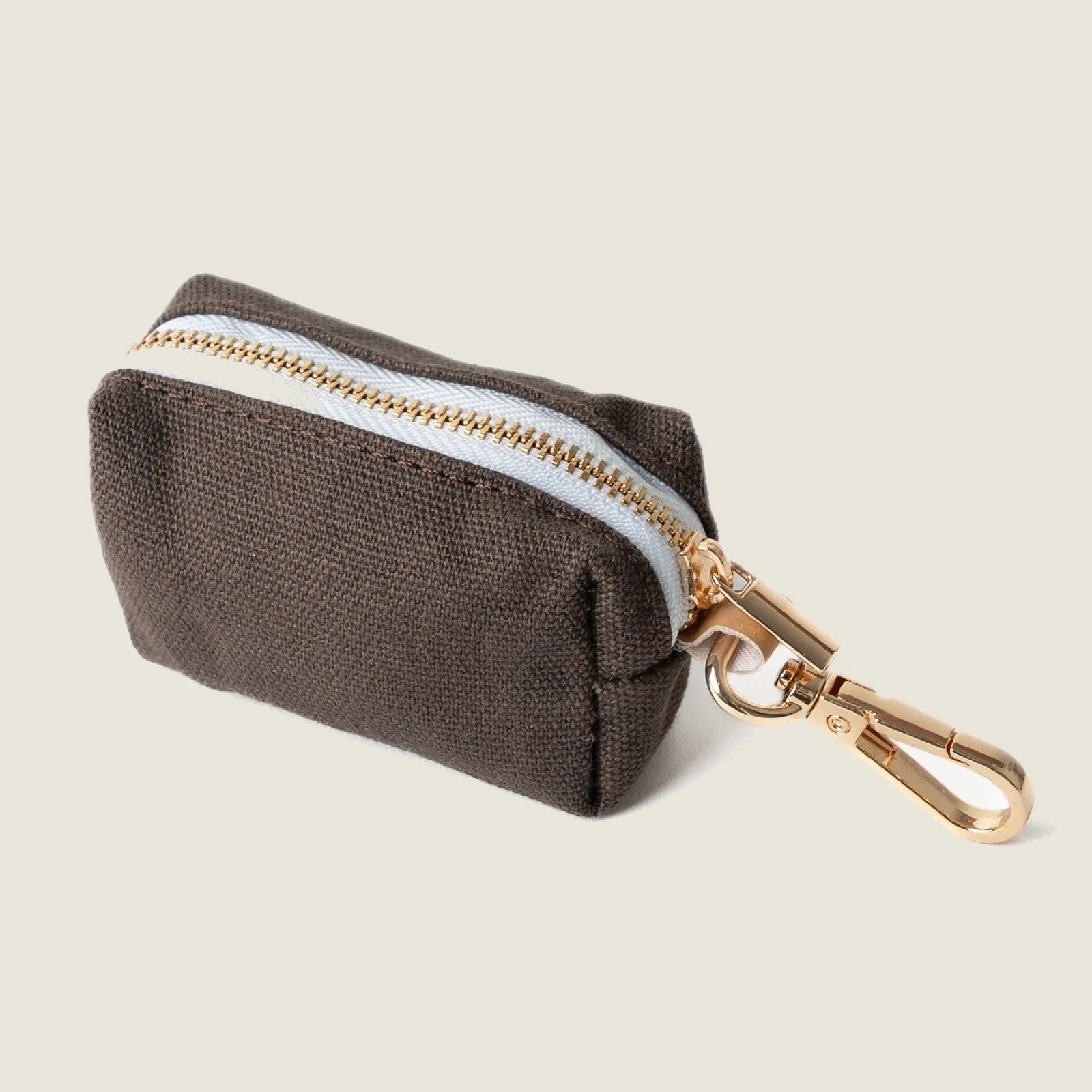 Compact brown poop bag holder with gold zipper, featuring a clip for easy attachment to a leash.