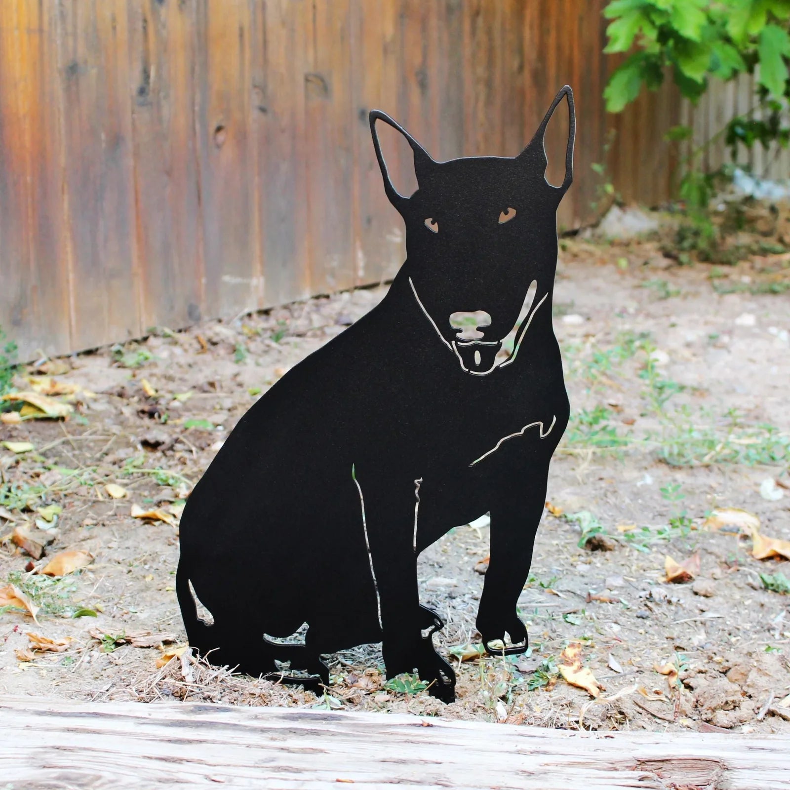 Bull Terrier silhouette in matte black metal, set against a natural outdoor backdrop, showcasing its detailed design.