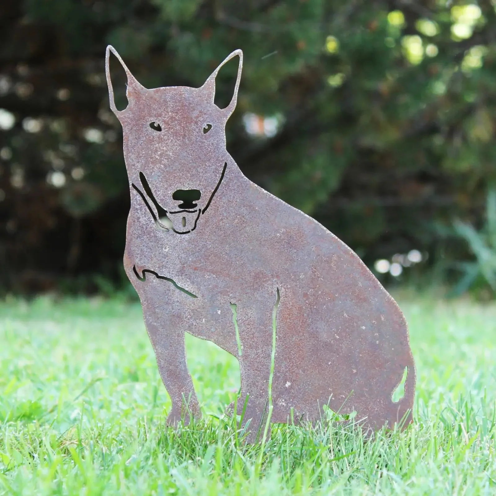 Bull Terrier silhouette in Corten steel, featuring a rustic rust patina, displayed on grass in a garden setting.