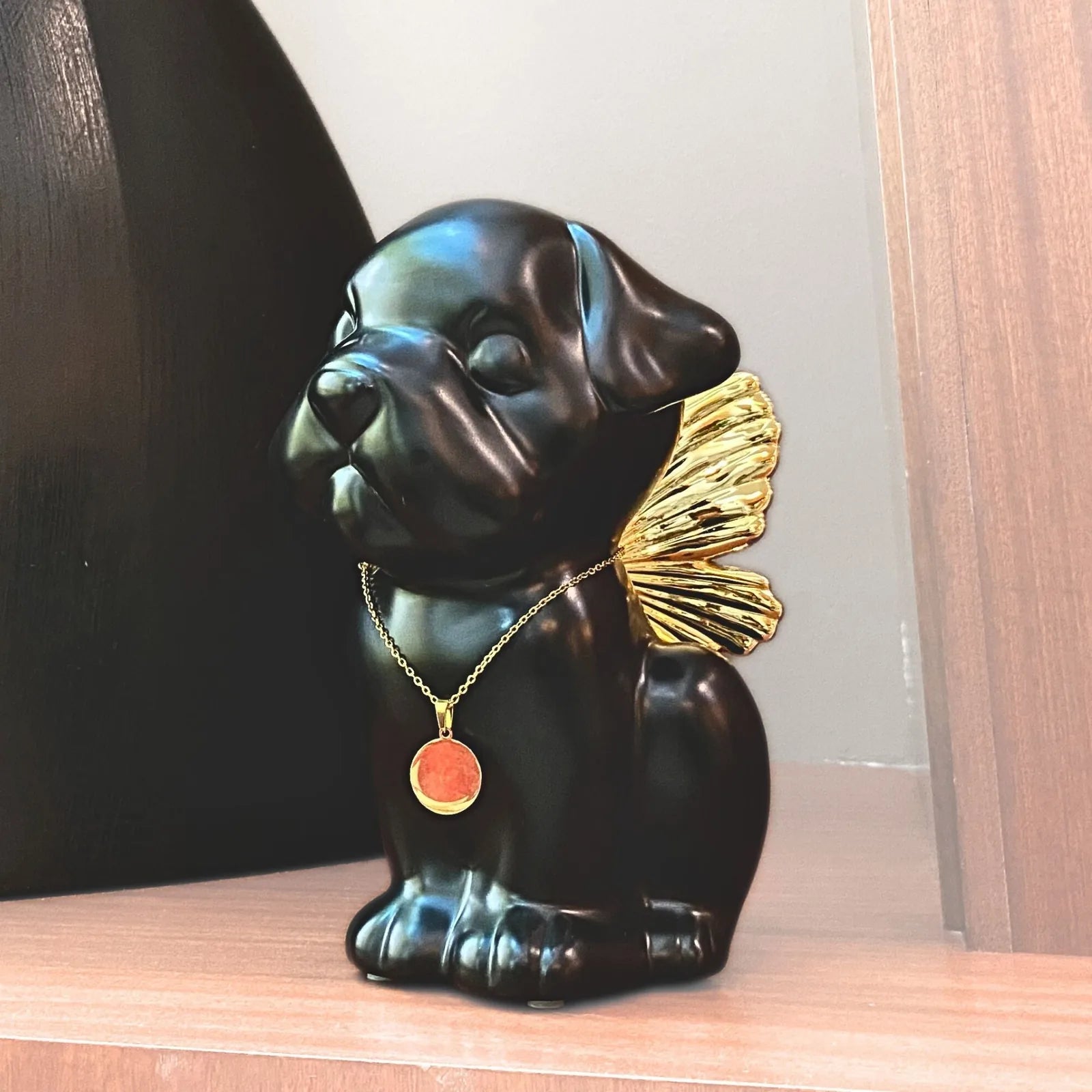 Handcrafted black dog urn with gold wings, featuring a pendant, perfect for memorializing beloved pets.
