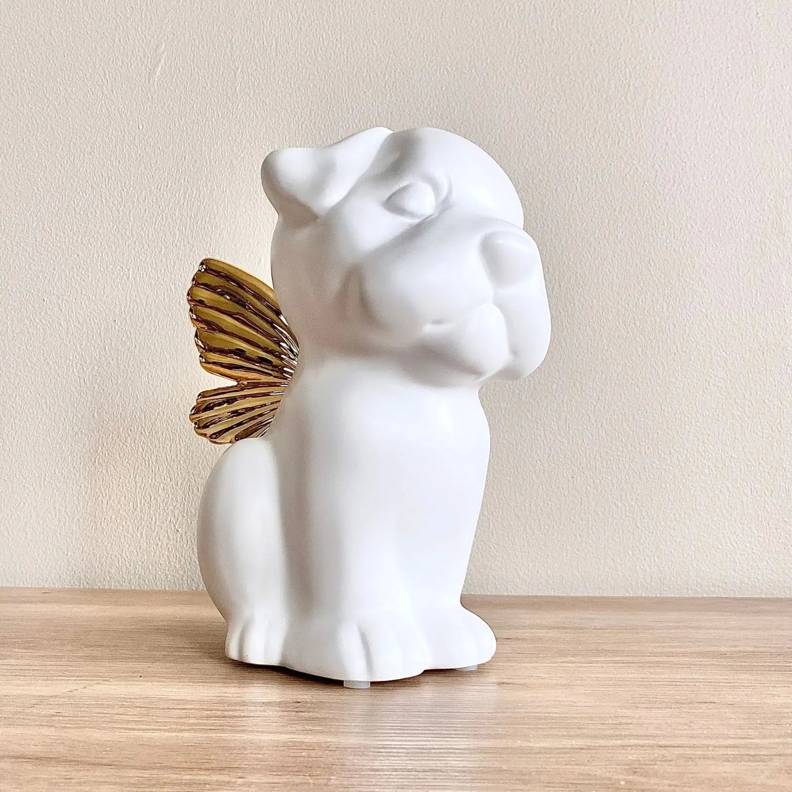 Handcrafted white dog urn featuring gold wings, perfect for memorializing a beloved pet.