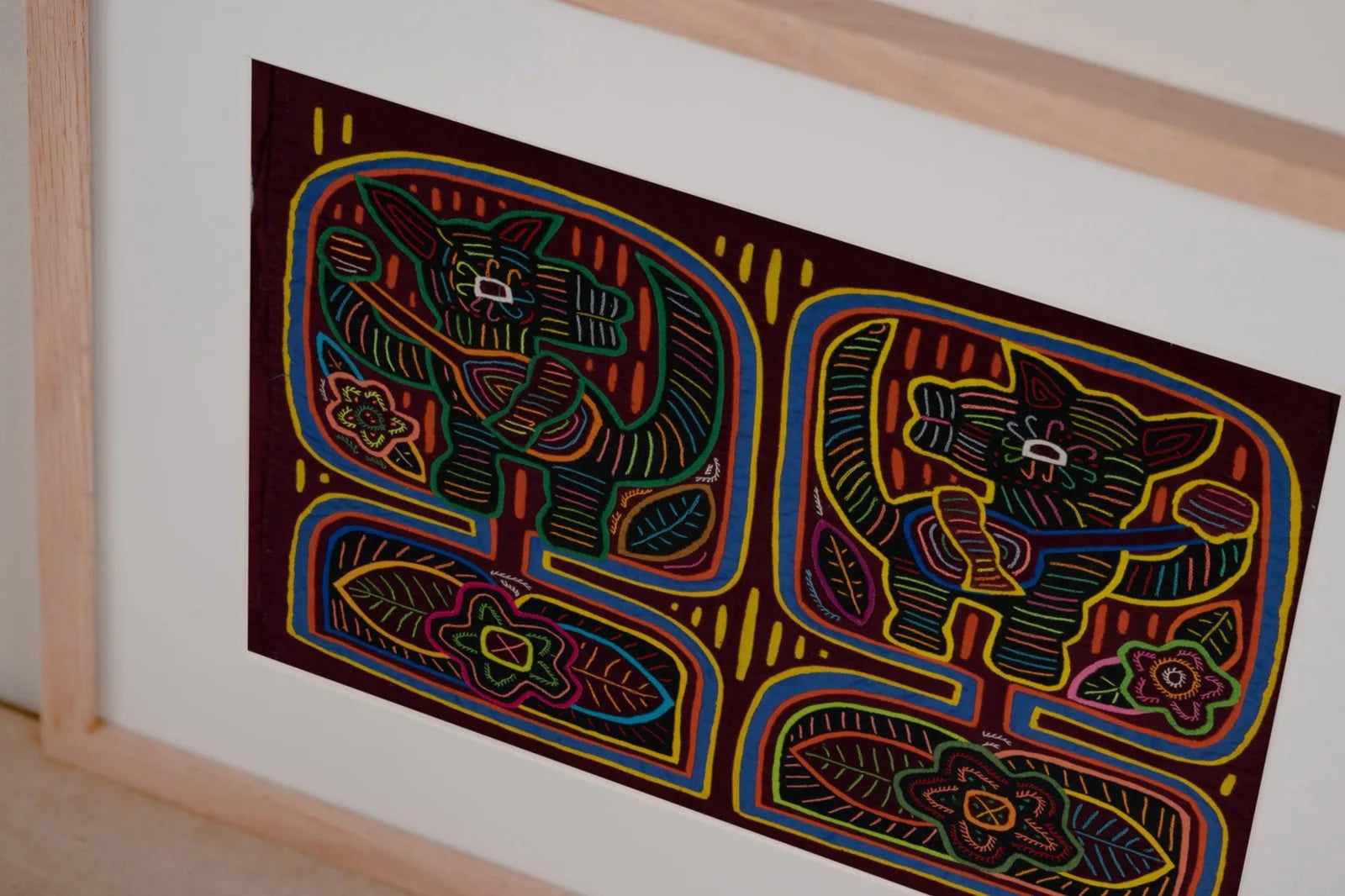 Burgundy tapestry featuring colorful hand-stitched dog and floral designs in a reverse appliqué style.