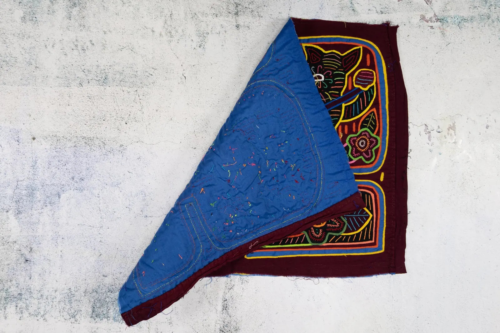 Burgundy and blue hand-stitched Mola tapestry featuring a puppy playing a banjo with colorful floral designs.