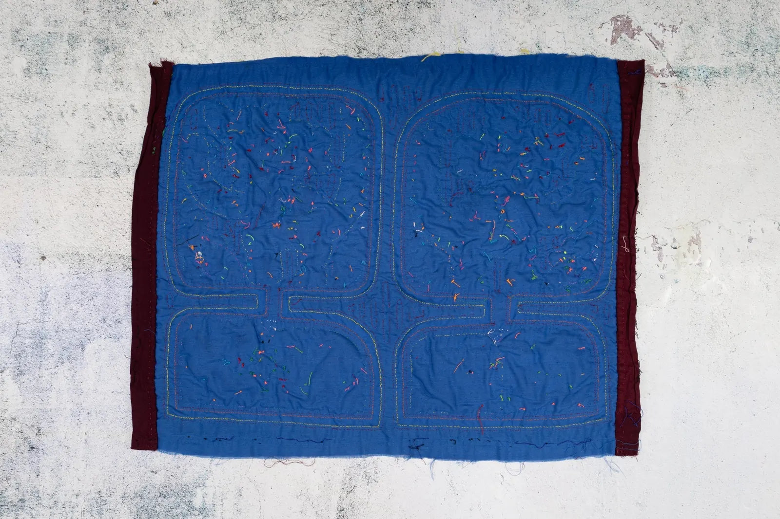 Burgundy-bordered blue tapestry featuring colorful hand-stitched details in a unique Mola design by TraderBrock.
