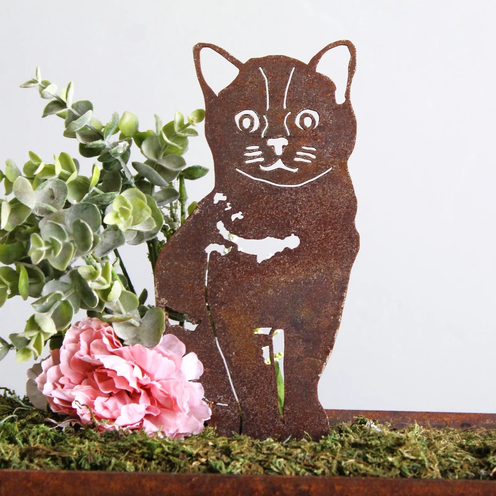Burmese metal silhouette in weathered Corten steel, featuring a cat design with greenery and a pink flower backdrop.