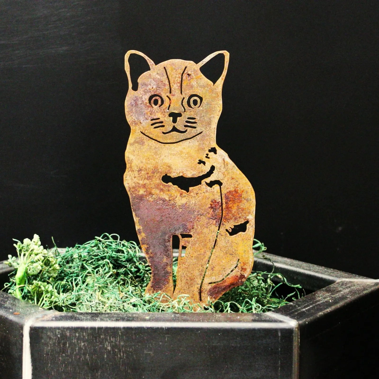 Rustic Burmese metal silhouette of a seated cat, crafted from weathering steel, displayed in a black planter with green fi...