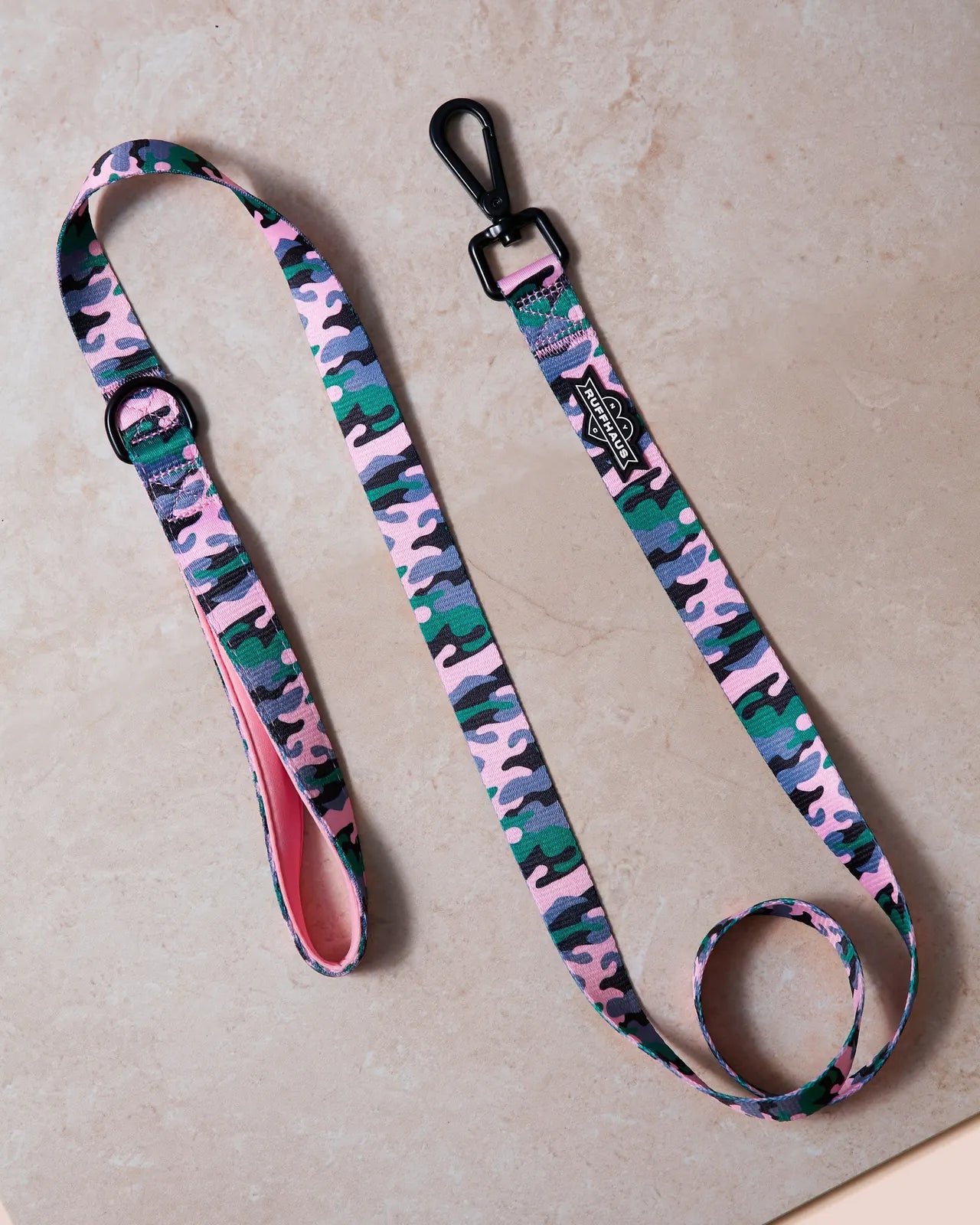 Pink camouflage dog leash by RUFFHAUS NYC with neoprene handle and swivel snap clasp on textured surface.