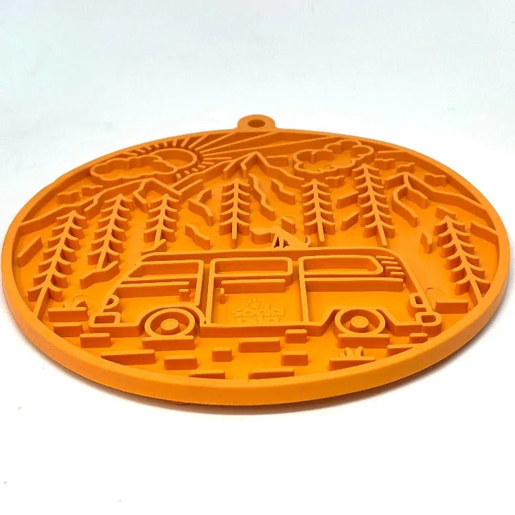 Orange silicone lick mat featuring a retro camper van design, trees, and a sun, ideal for enriching playtime for dogs.