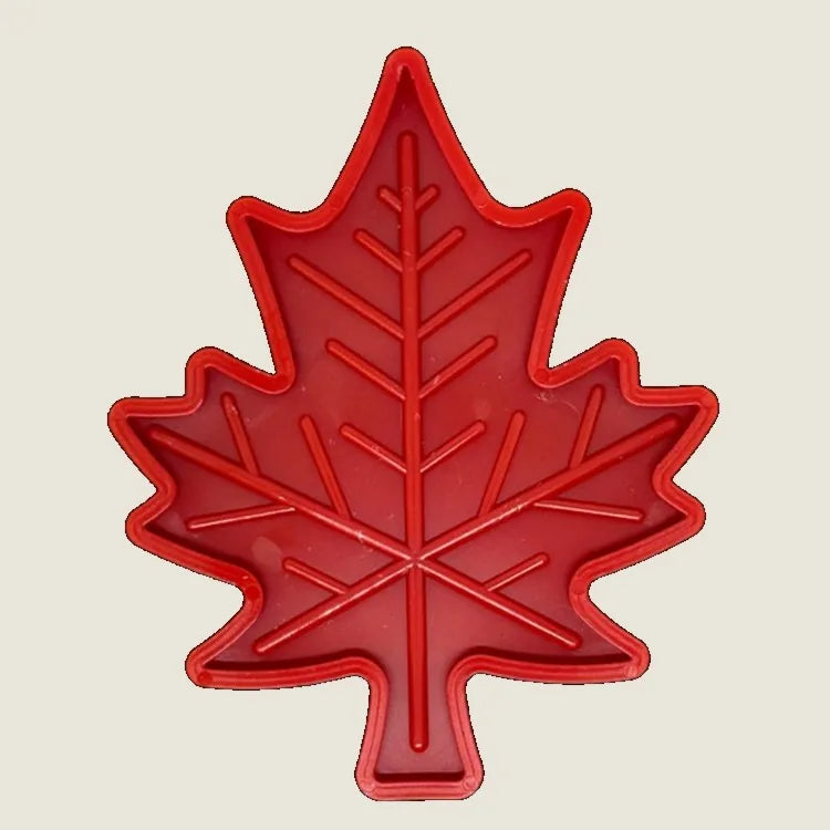 Bright red nylon dog chew toy shaped like a Canadian maple leaf, featuring textured grooves for added grip and treat stuff...