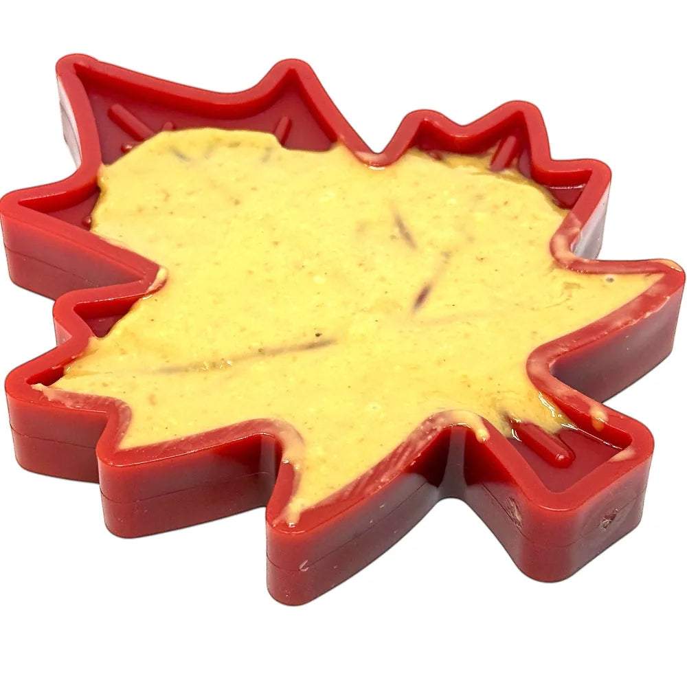 Red Canadian maple leaf-shaped nylon chew toy filled with creamy treat, designed for durable dog play and enrichment.