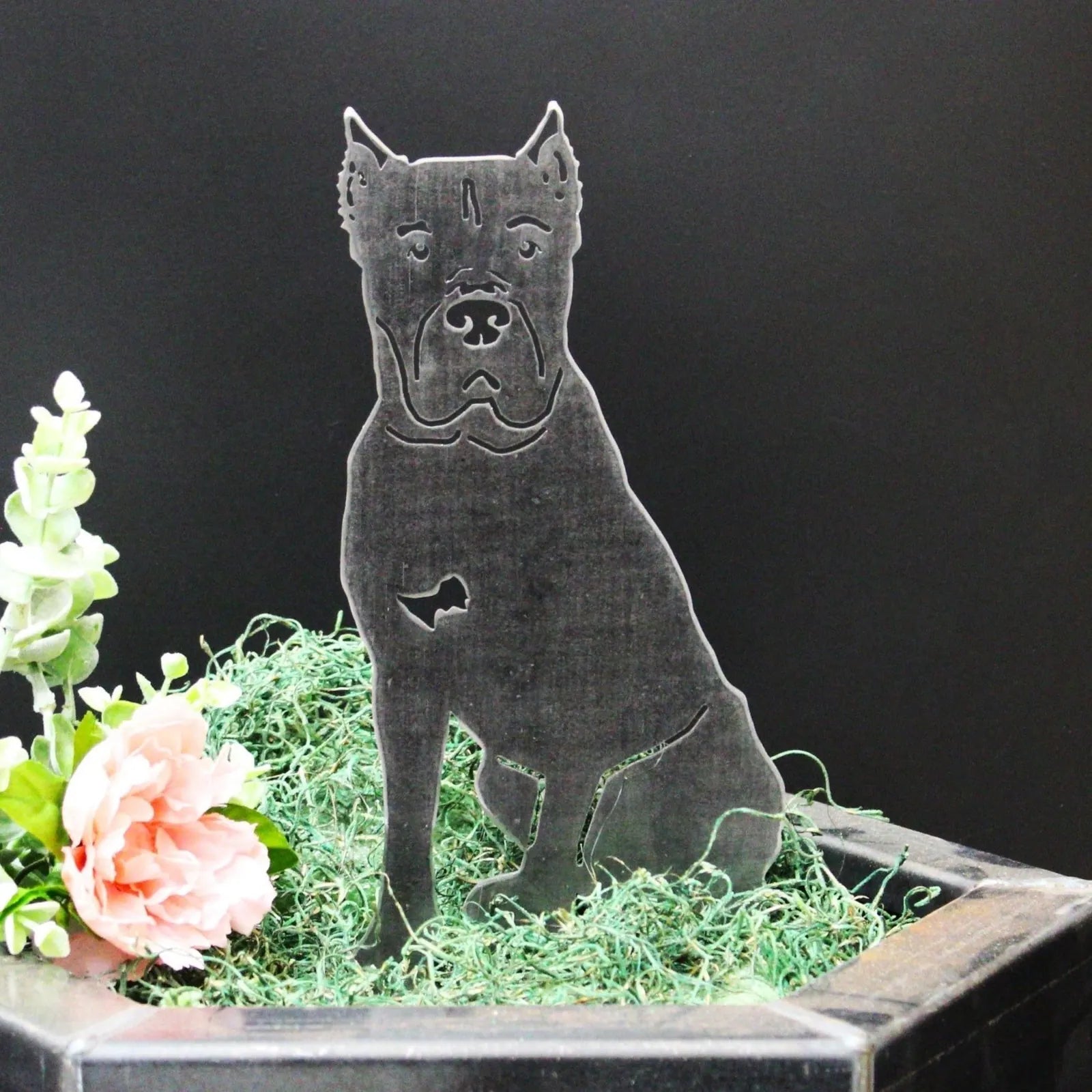 Cane Corso metal silhouette in matte black, showcasing a dog design among green decorative moss and flowers.