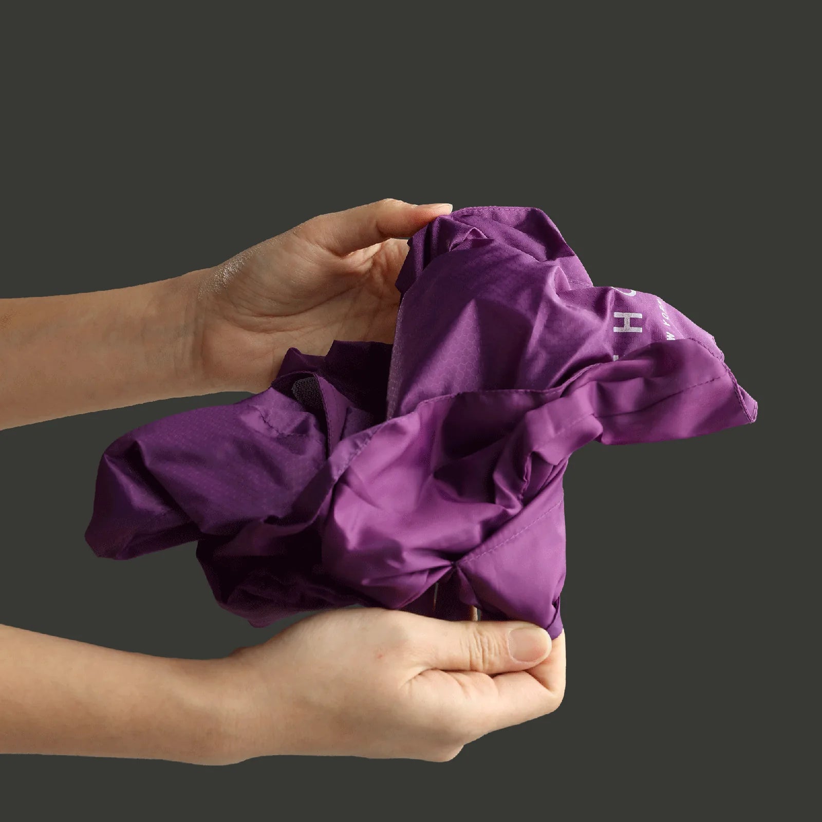 Compactly folded green Capsule Raincoat by pehomnyc, showcasing lightweight, water-repellent fabric for dogs.