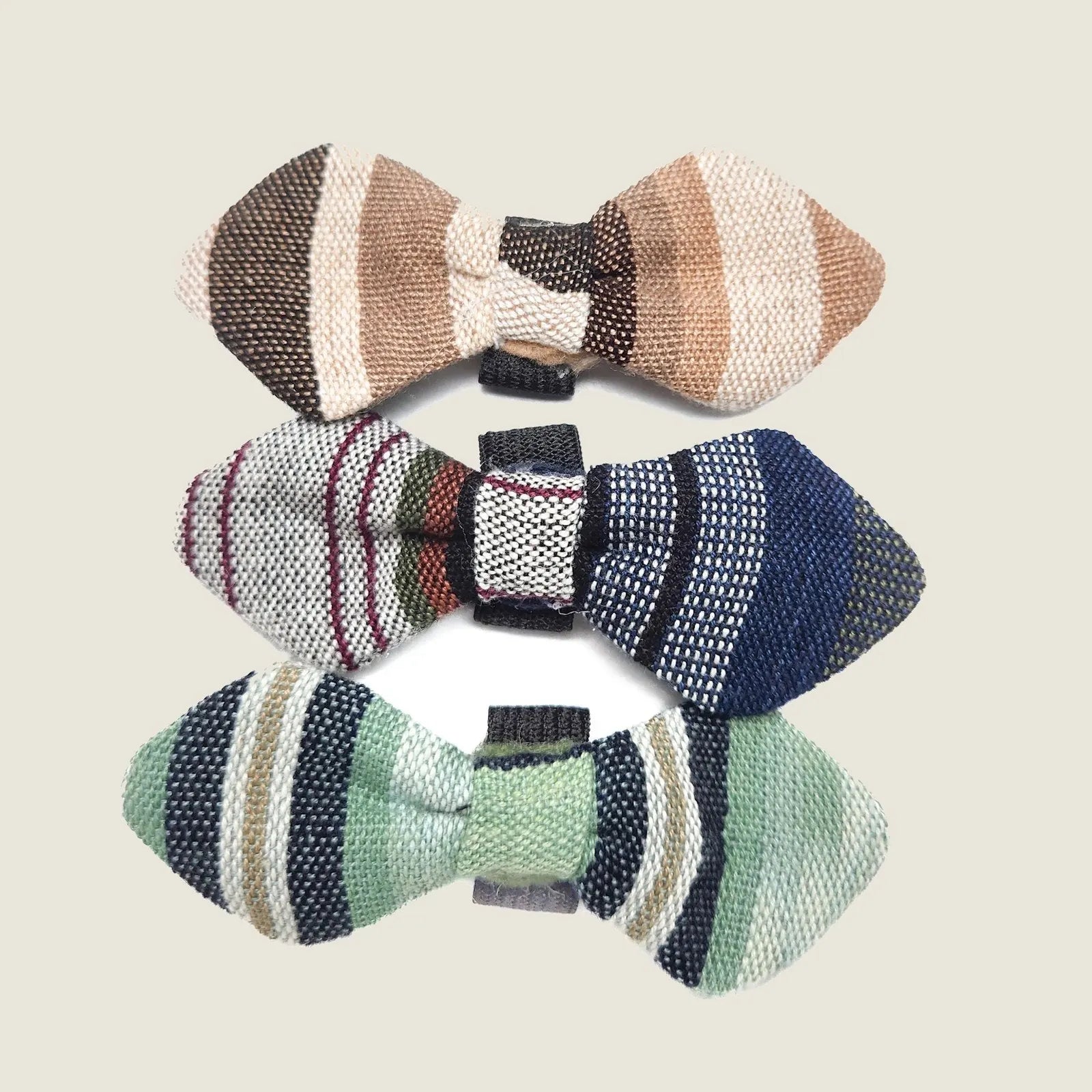 Handcrafted bow ties in earthy tones, featuring stripes in beige, green, and blue, perfect for pet accessories.