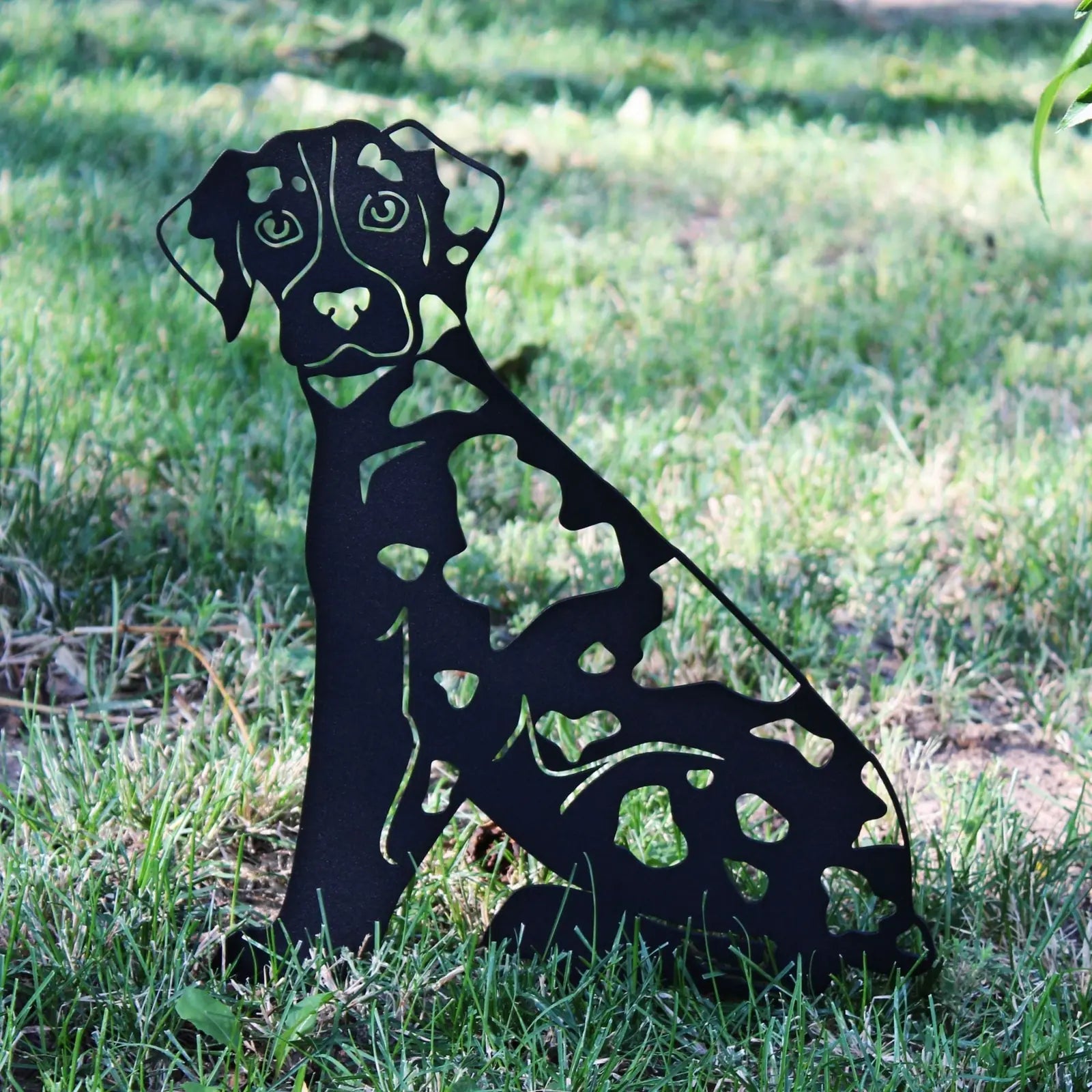 Black metal silhouette of a Catahoula Leopard Dog sitting on grass, showcasing cut-out patterns and sturdy design.