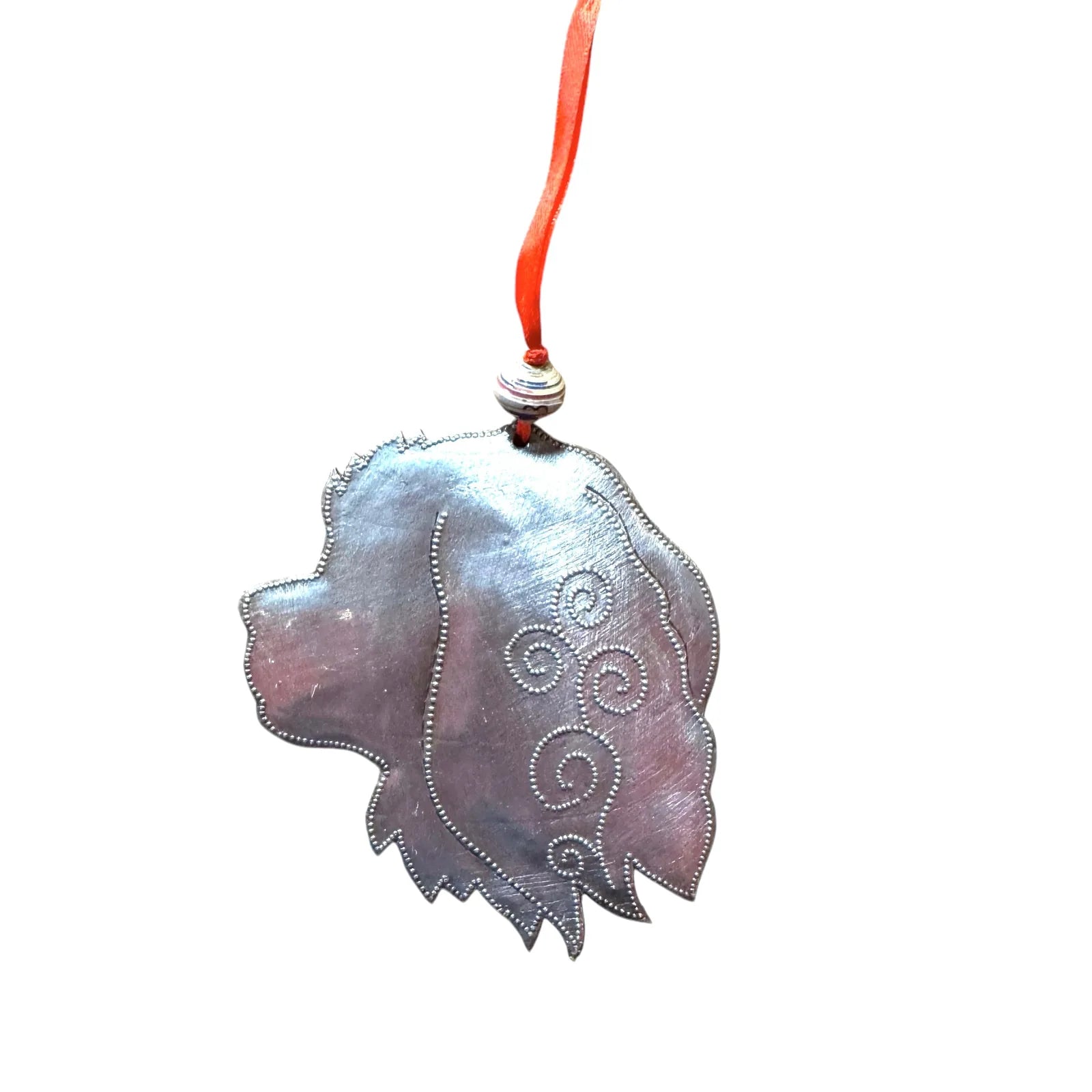 Handmade steel drum ornament of a Cavalier King Charles dog head, featuring swirling designs and a red ribbon.