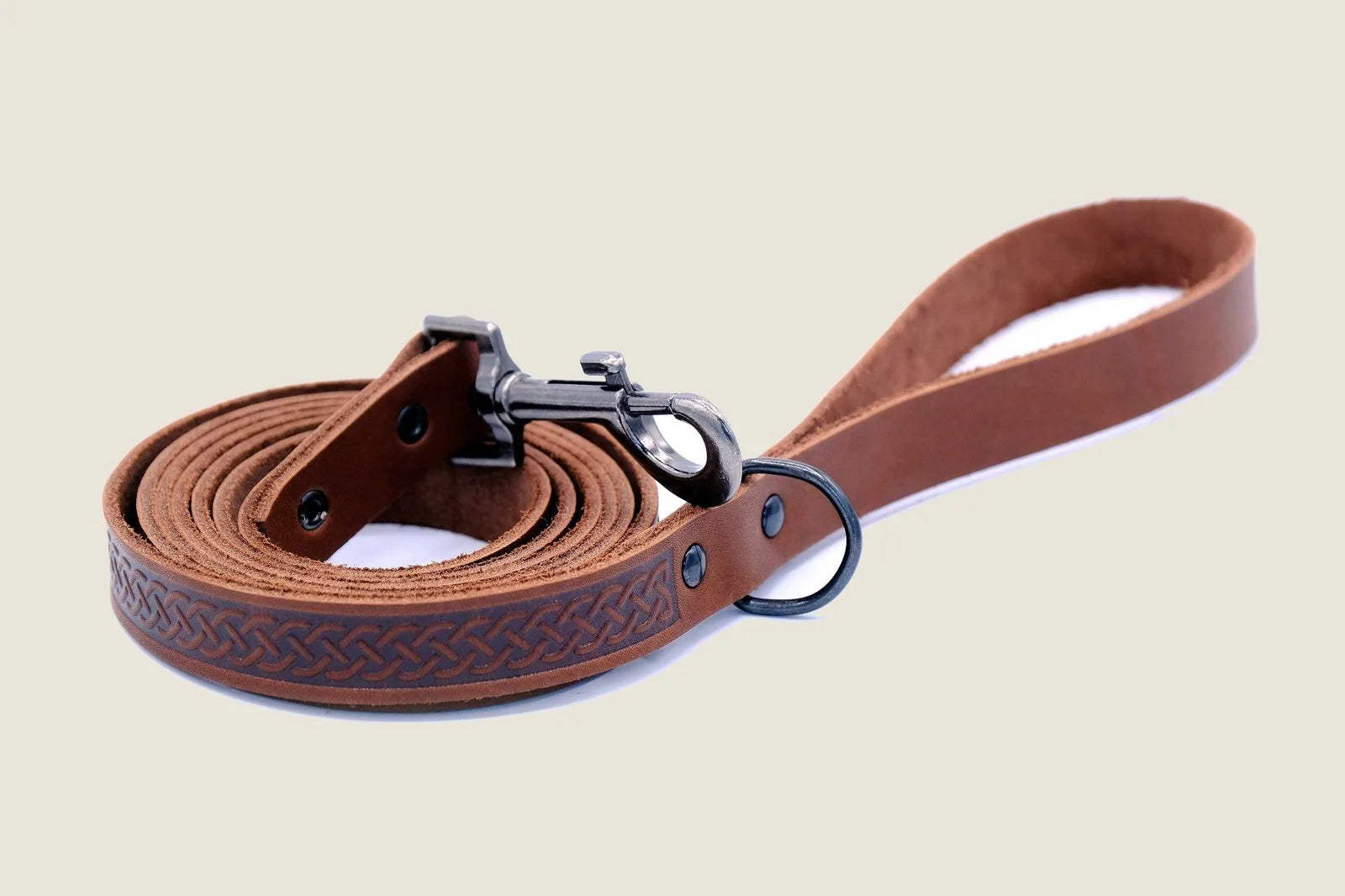 Chocolate leather dog leash featuring a Celtic design and black hardware, rolled for easy handling.