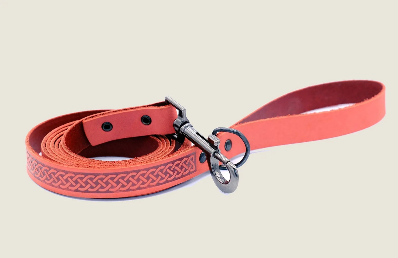 Quality leather dog leash in coral with a braided pattern and a durable metal clip, perfect for walks and adventures.