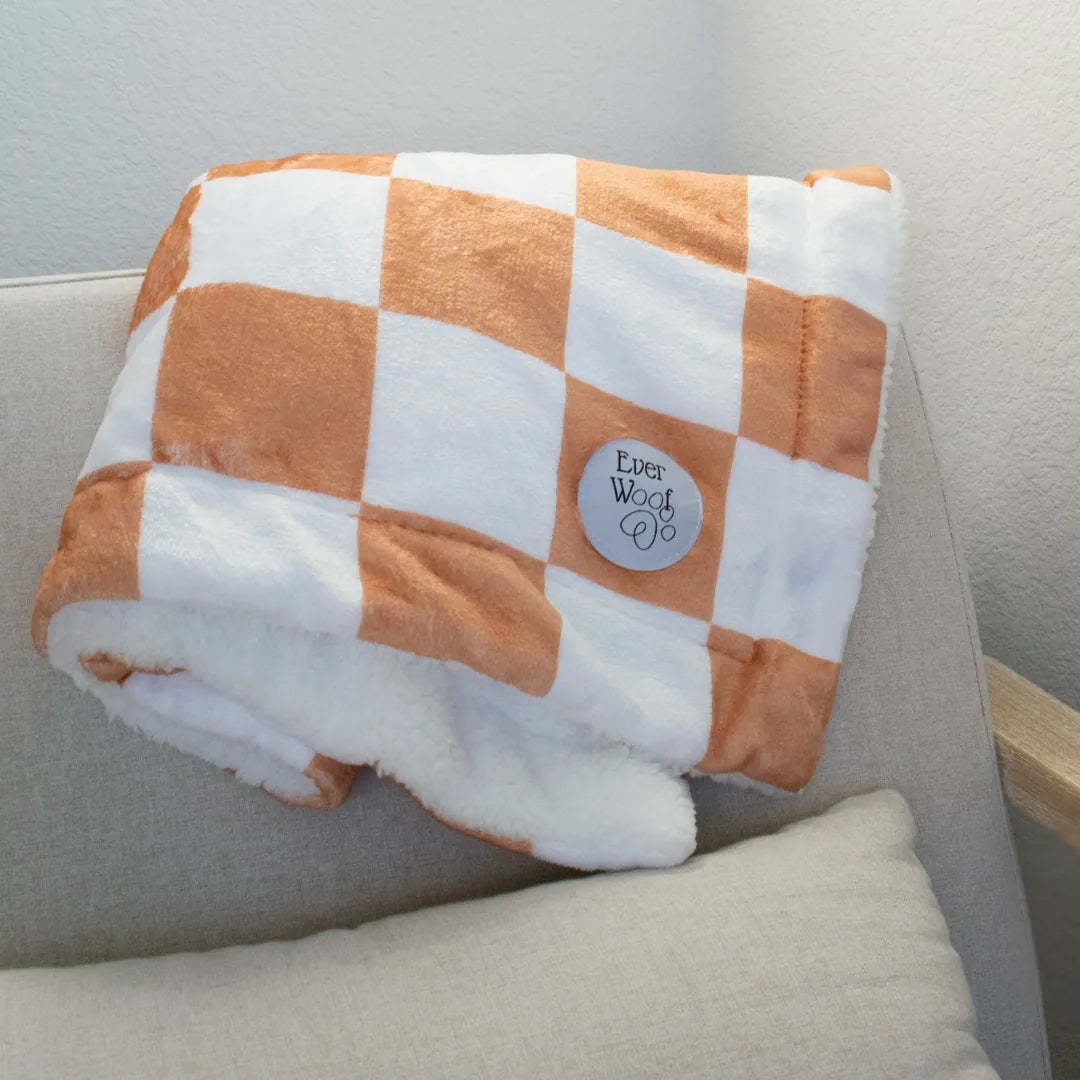 Cozy orange and white checkered dog blanket with a cream sherpa underside, featuring the EverWoof logo.