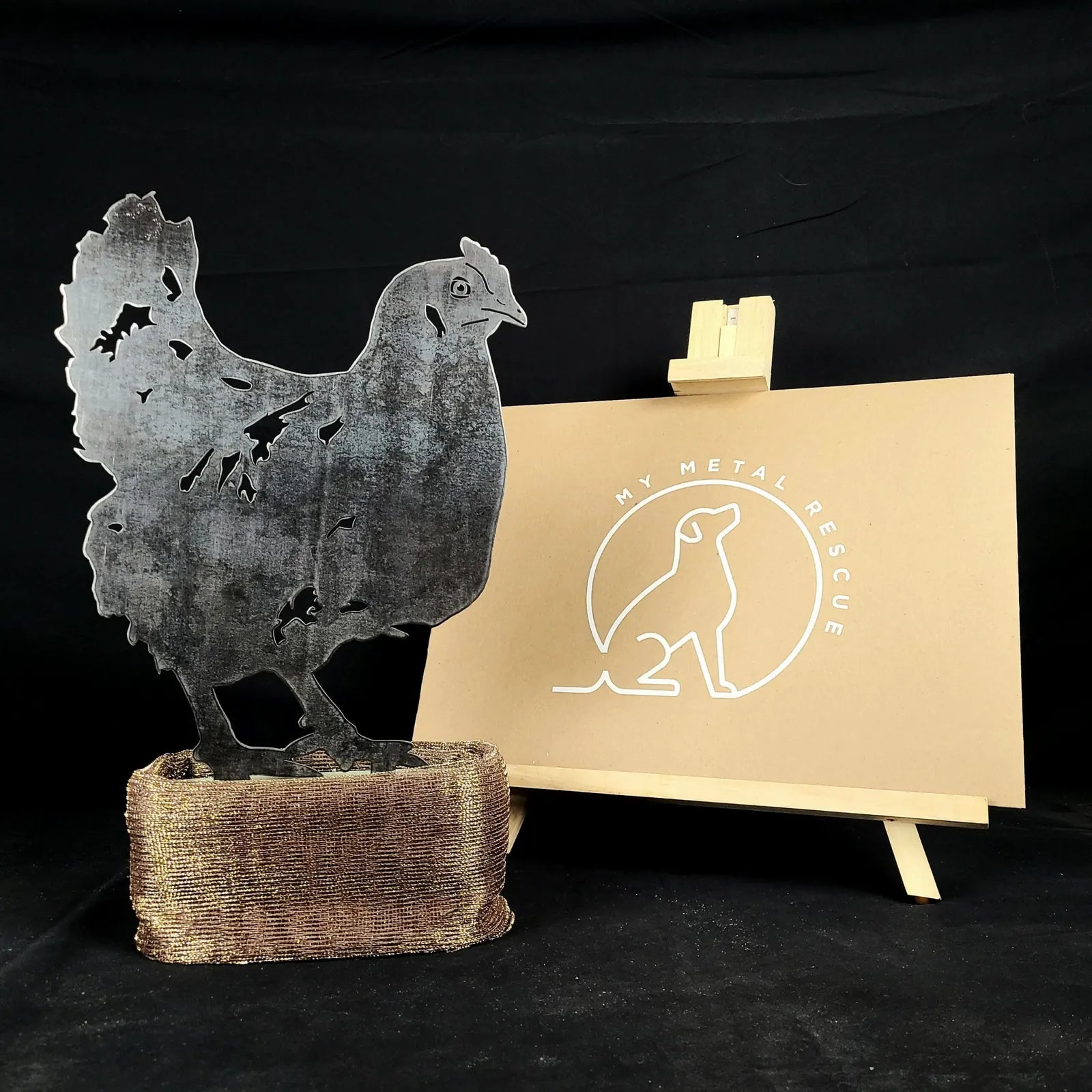 Rustic chicken silhouette made from weathered steel, displayed beside a My Metal Rescue logo on a beige board.