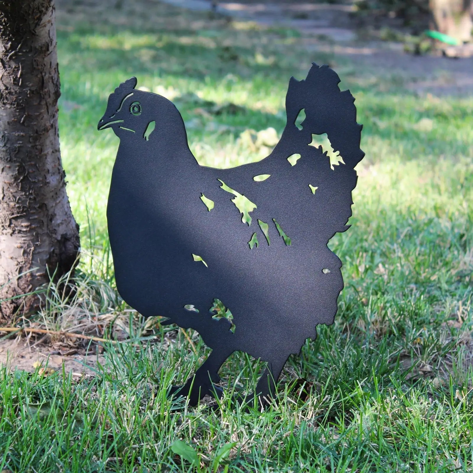 Black metal chicken silhouette standing in grass, designed for outdoor garden decor by My Metal Rescue.