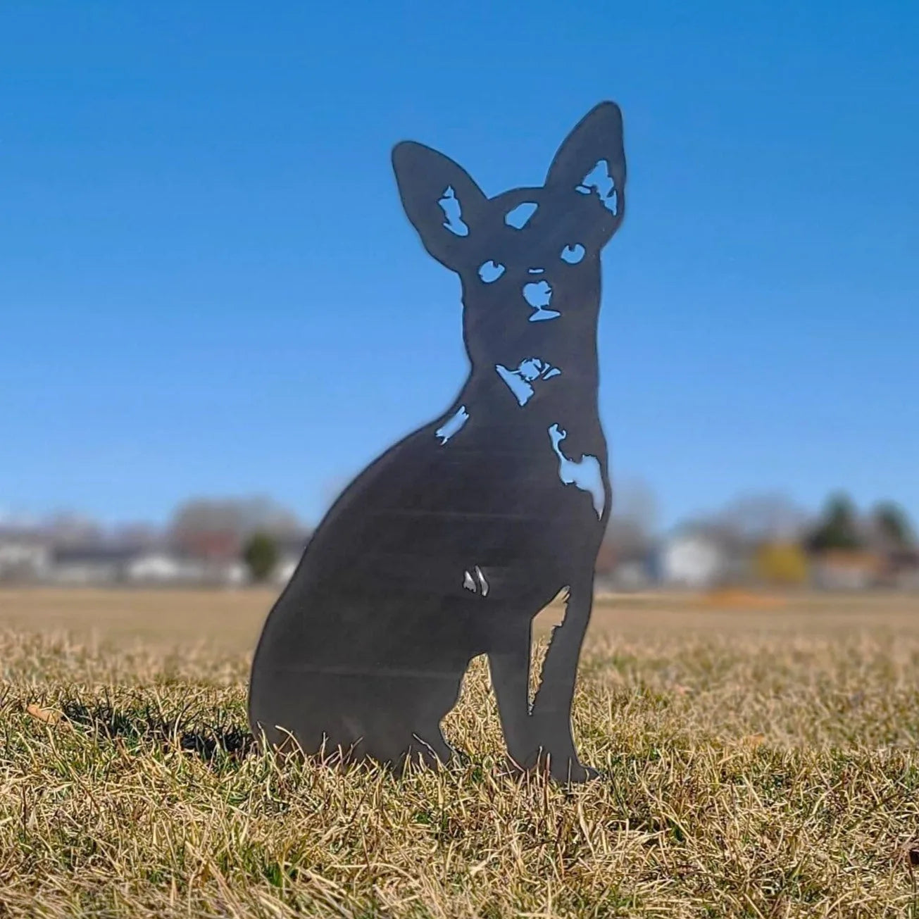 Black metal silhouette of a sitting Chihuahua dog in a grassy field, showcasing durable outdoor decor.