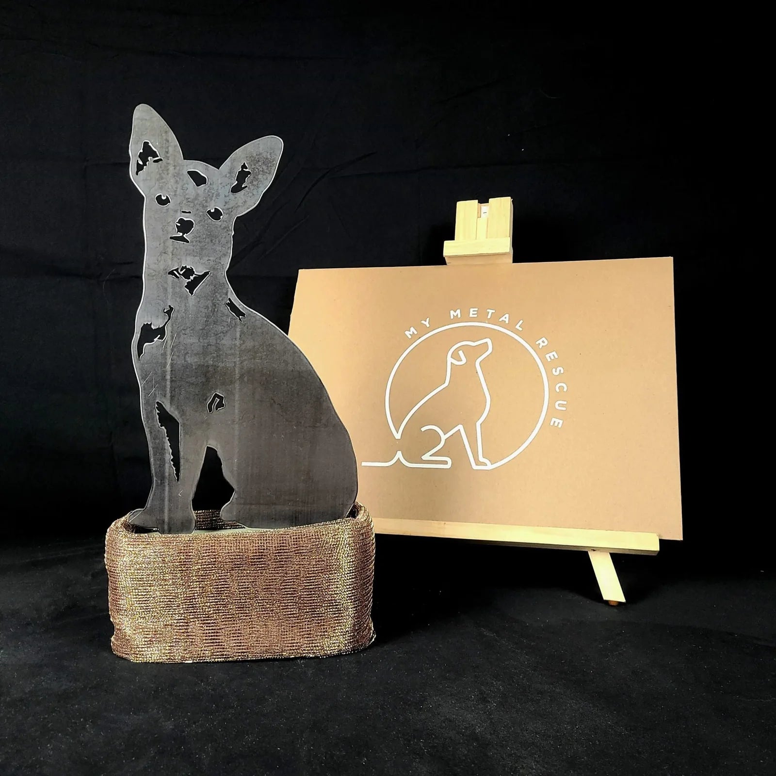 Chihuahua metal silhouette in Corten steel, elegantly displayed on a textured base with a brand logo backdrop.