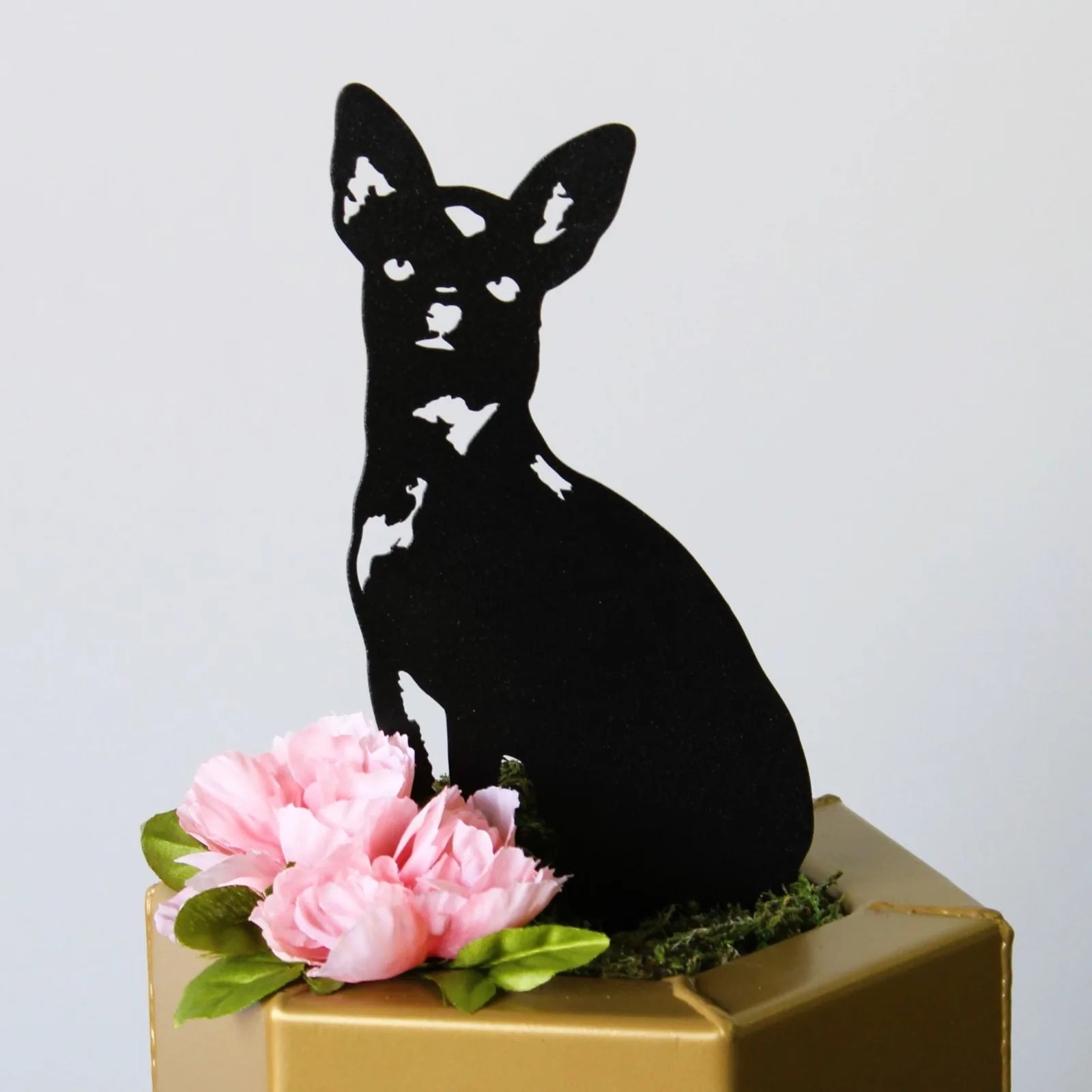 Black metal silhouette of a Chihuahua dog, surrounded by pink flowers on a decorative gold box.