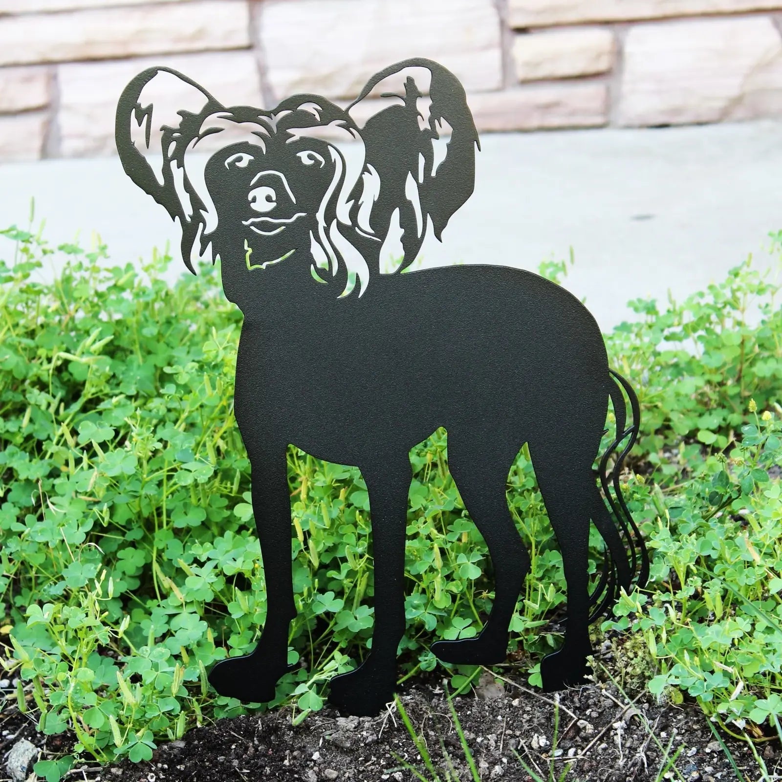 Black metal silhouette of a Chinese Crested dog standing among greenery, crafted for outdoor decor.