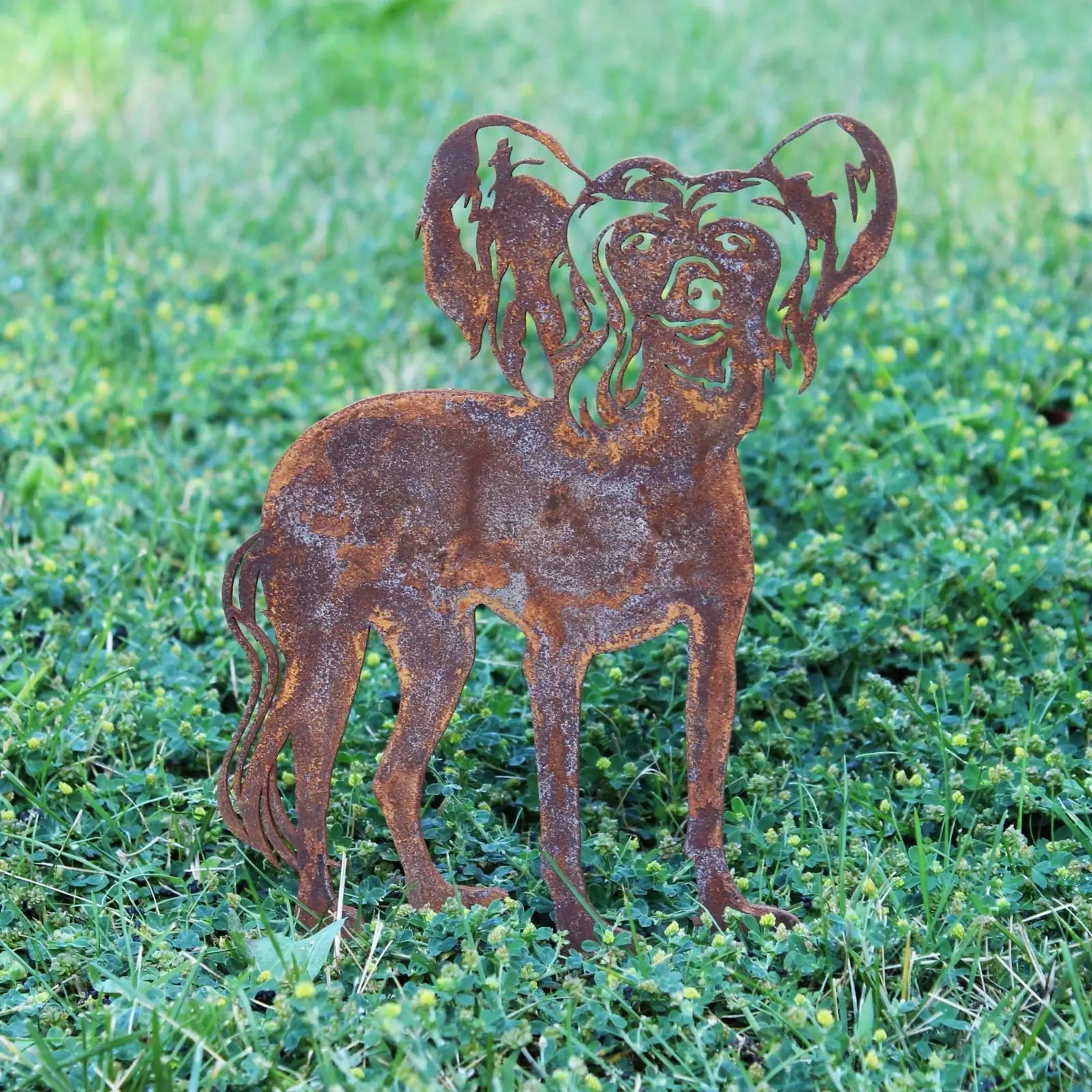 Handcrafted Corten steel silhouette of a Chinese Crested dog, showcasing a rustic patina in a garden setting.
