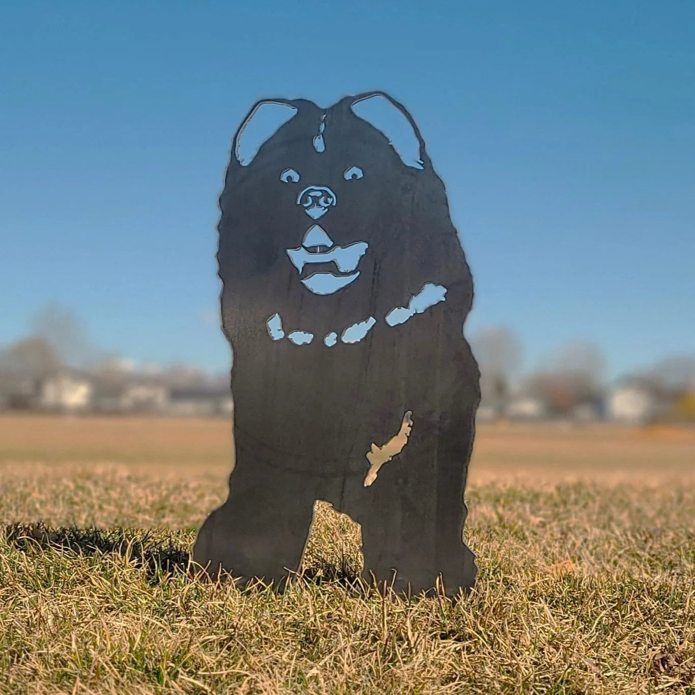 Chow Chow metal silhouette in matte black, standing on grass with a clear blue sky backdrop, perfect for outdoor decor.