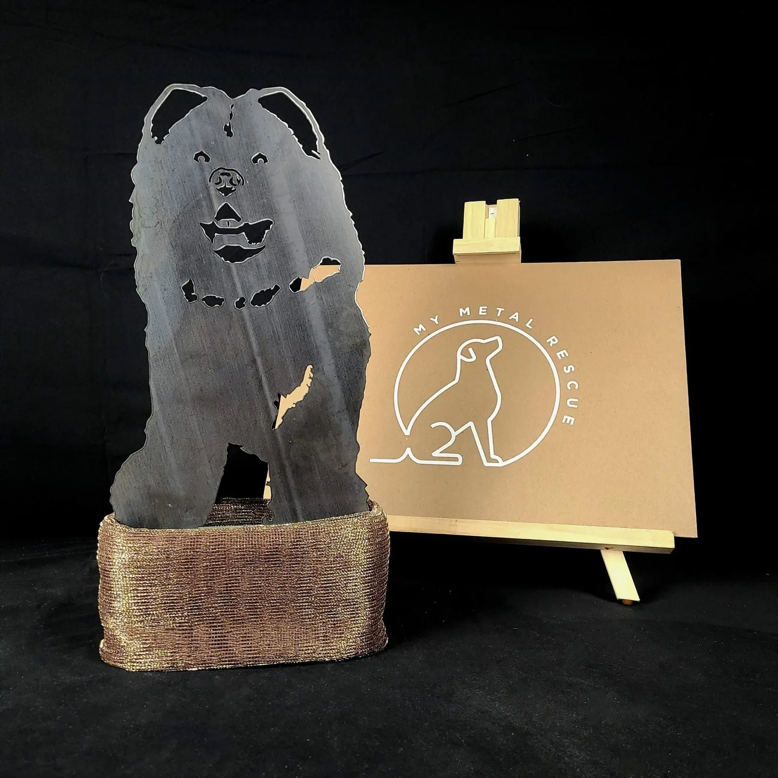 Chow Chow metal silhouette in black, displayed on a bronze base, with a My Metal Rescue sign in the background.