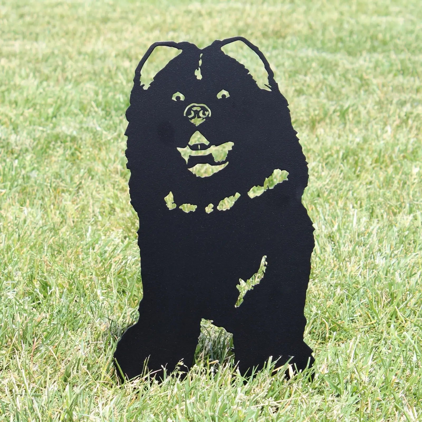 Black metal silhouette of a Chow Chow dog standing in green grass, designed for outdoor decor.
